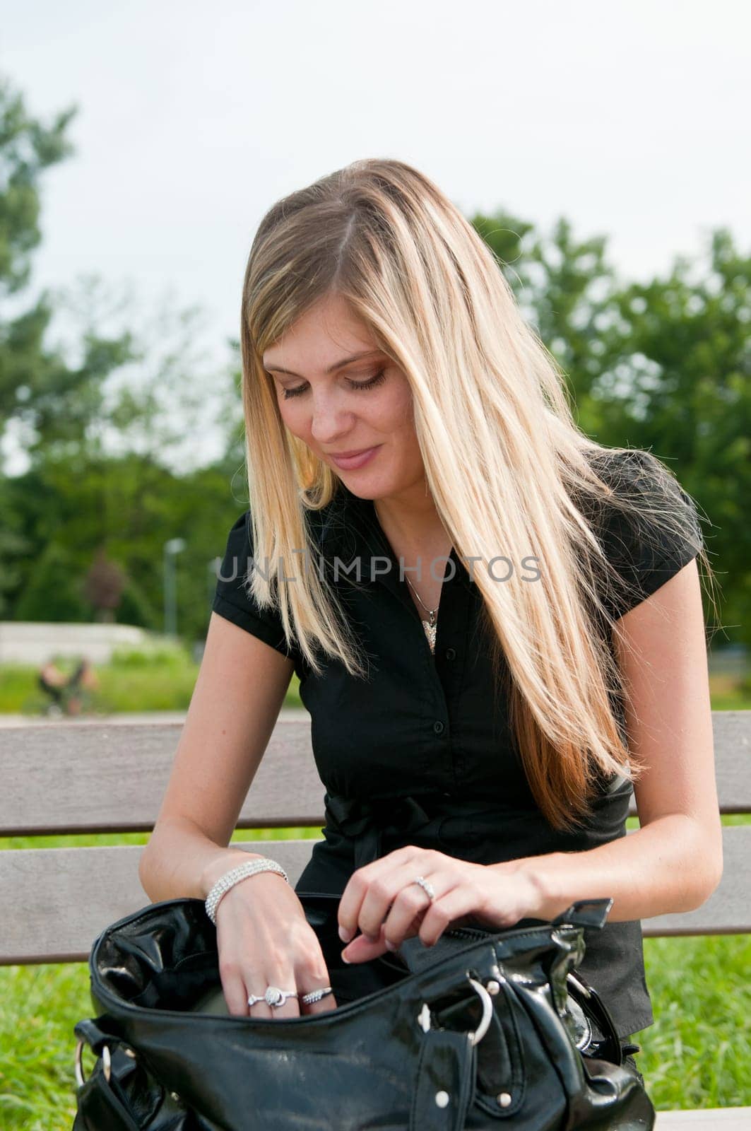 Young blond beautiful woman looking for something in her big hand bag