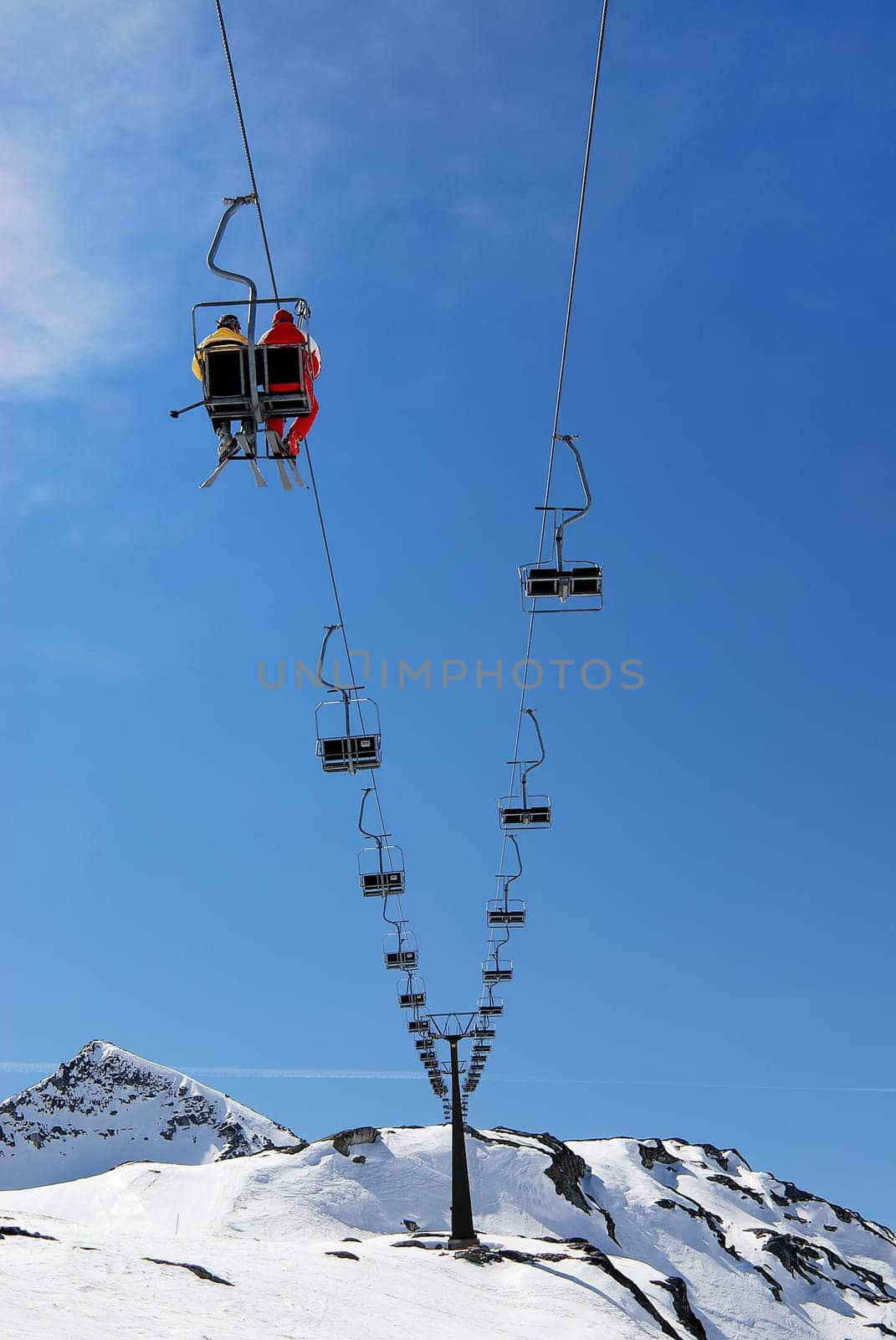 Winter snow scene of people sitting on emty ski lift