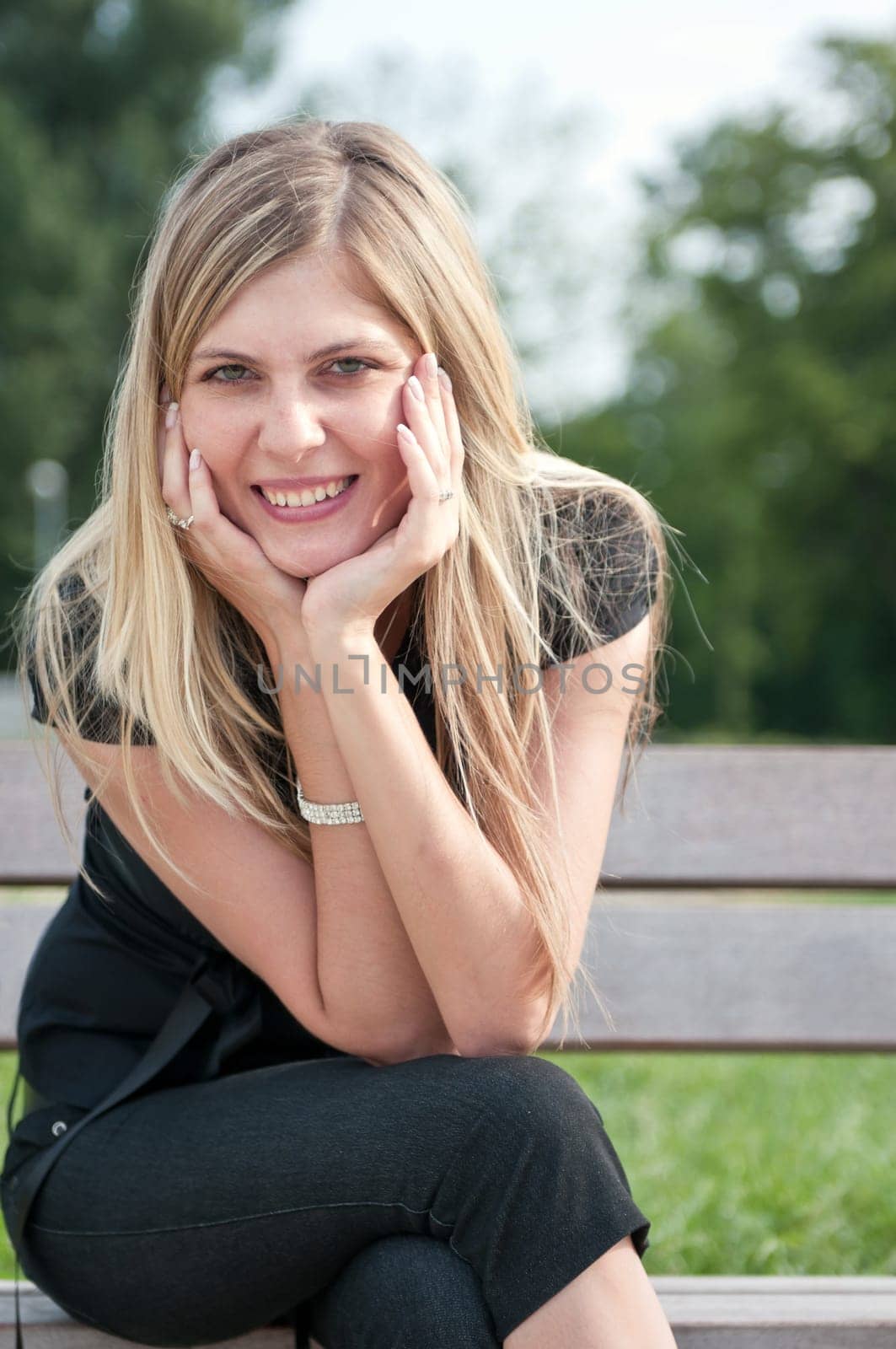 Portrait of young beautiful smiling woman siting on bench in park outside