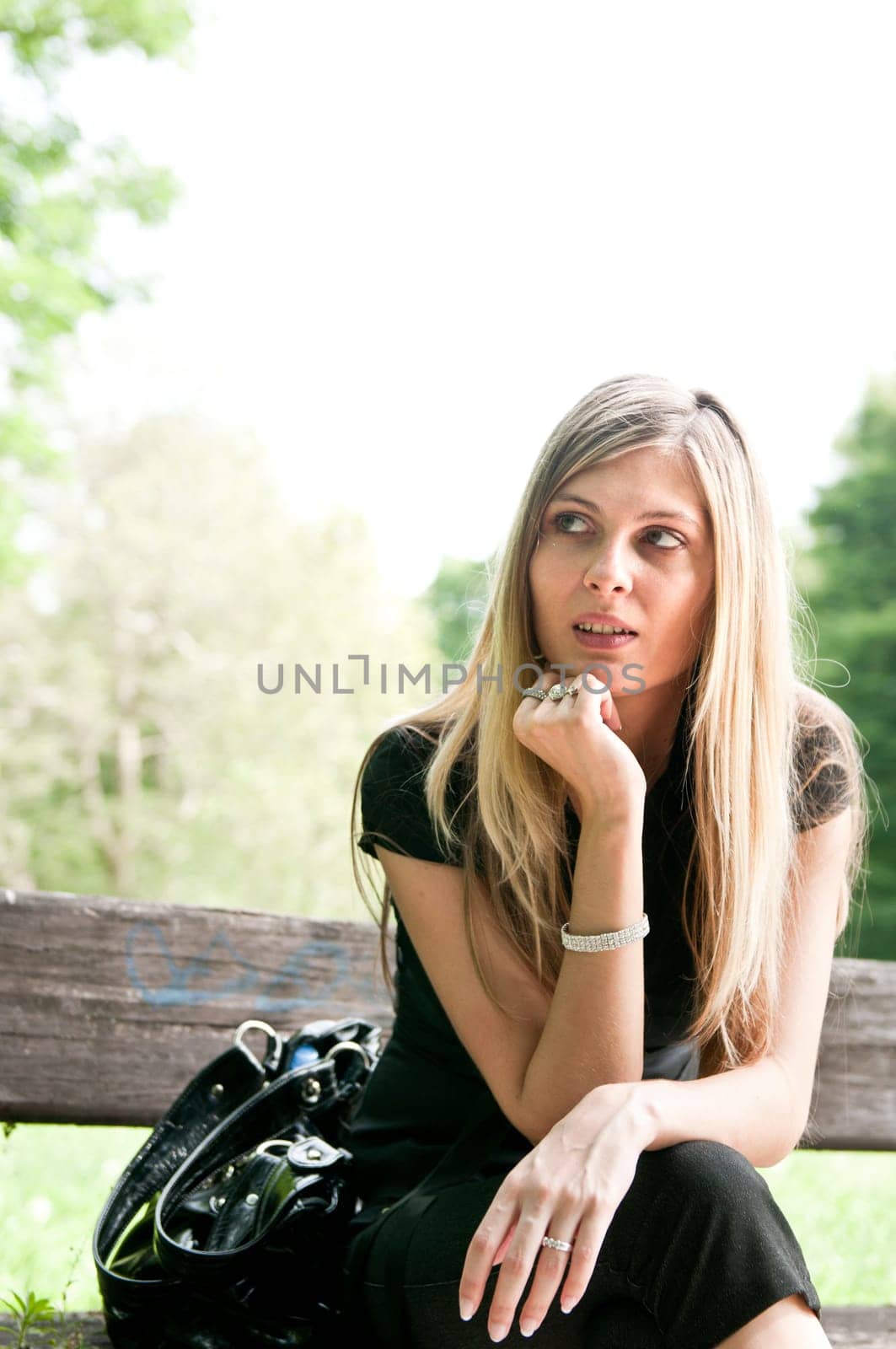 Portrait of young beautiful woman siting on bench in park