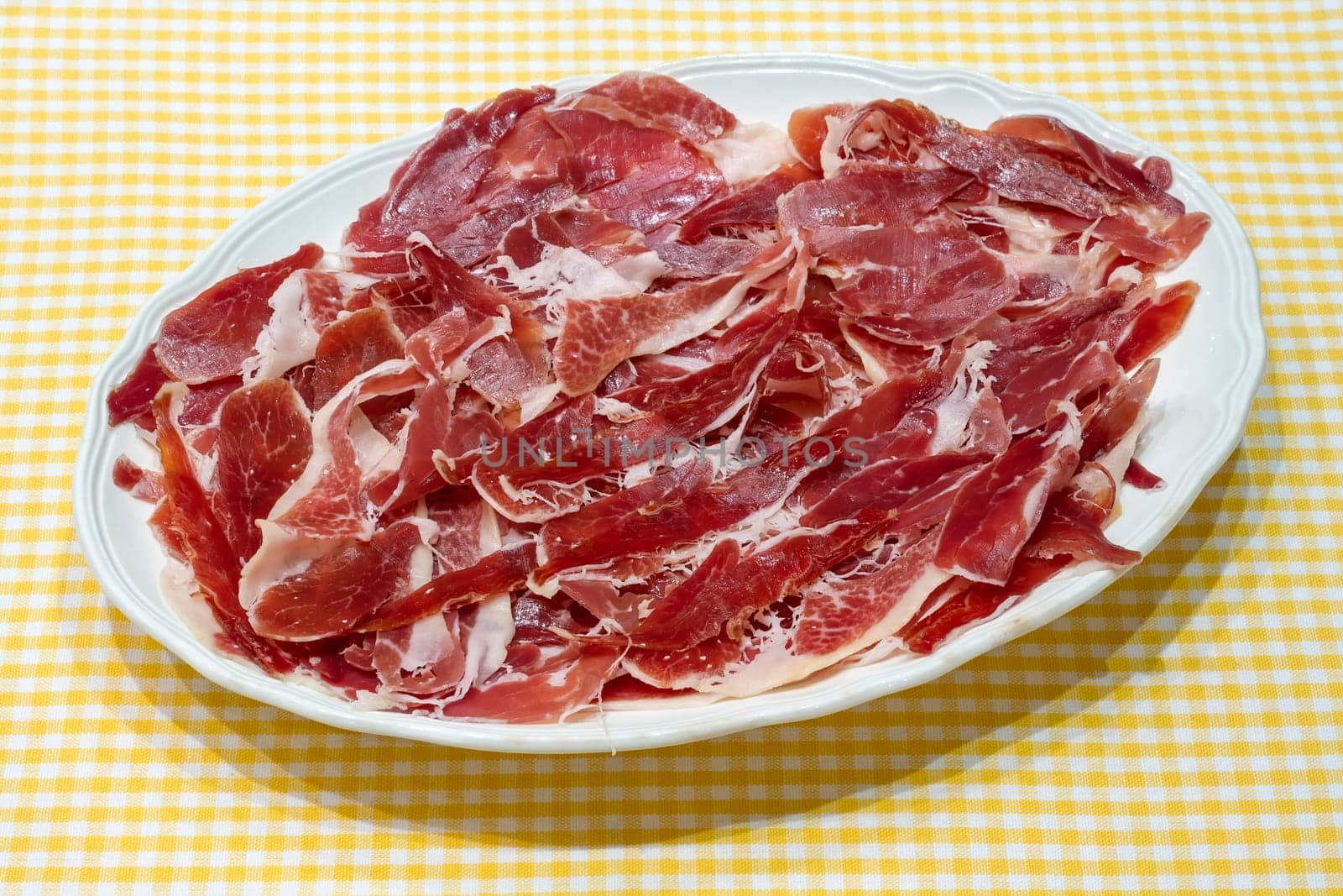 jamon serrano, spanish serrano ham presented on a plate on tablecloth