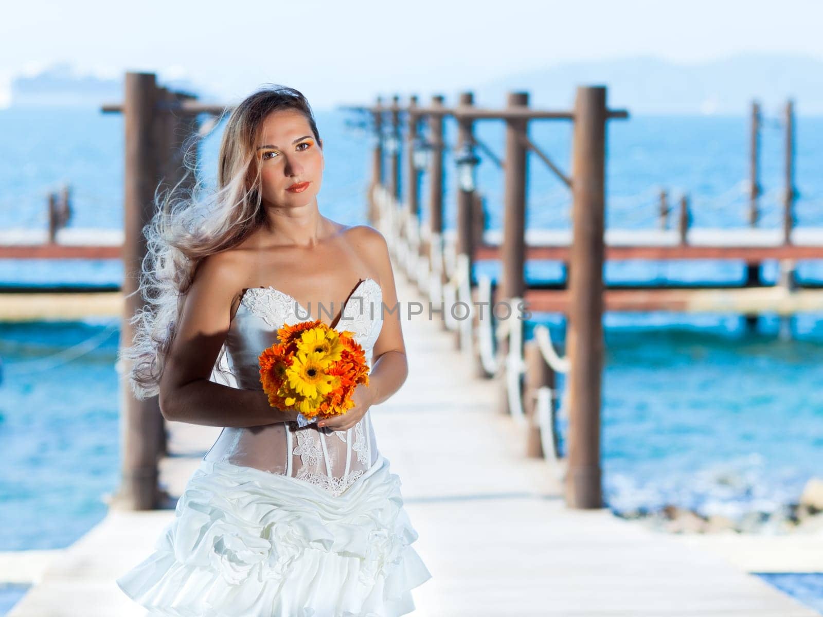Beautiful bride with wedding bouquet at the pier