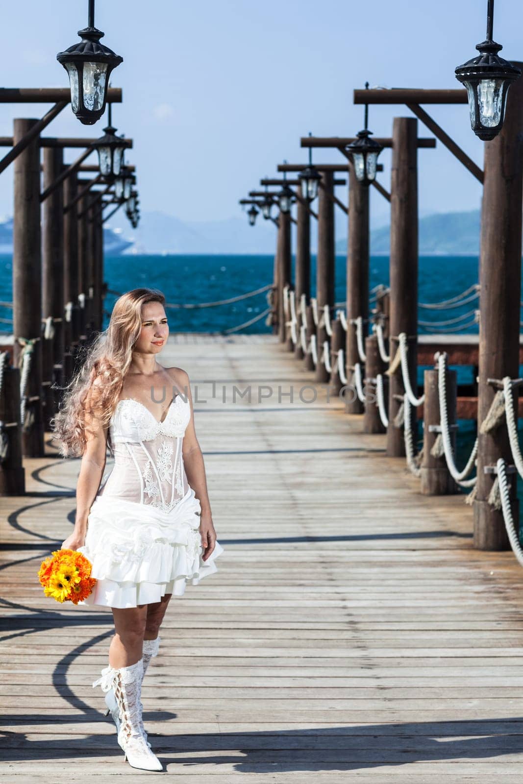 Beautiful bride with wedding bouquet at the pier