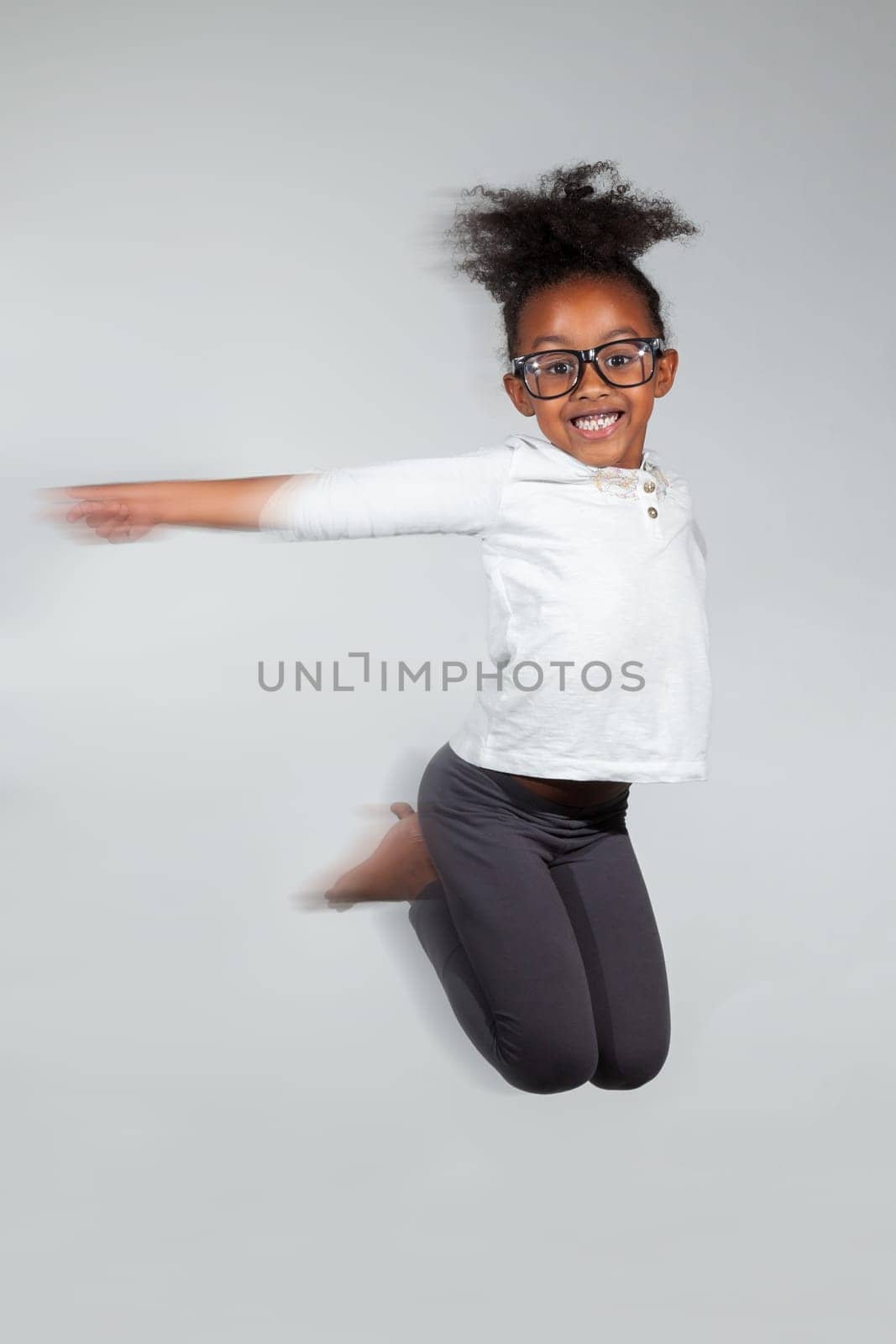 Portrait of cute Young African American girl jumping, over gray background