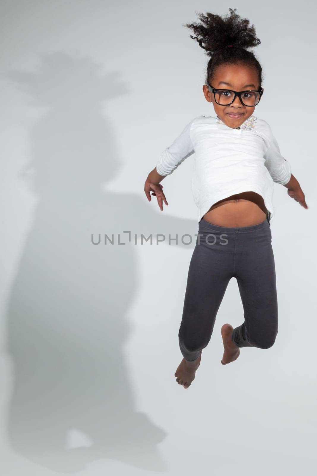 Portrait of cute Young African American girl jumping, over gray background