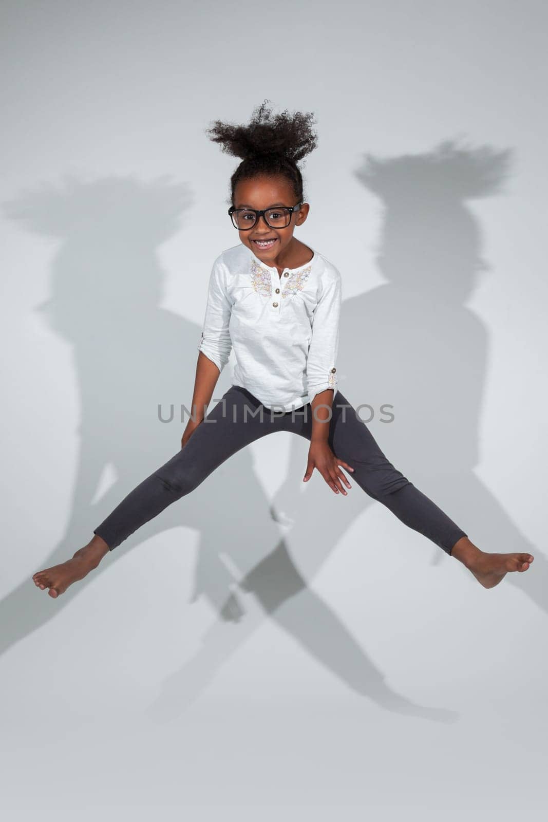 Portrait of cute Young African American girl jumping, over gray background