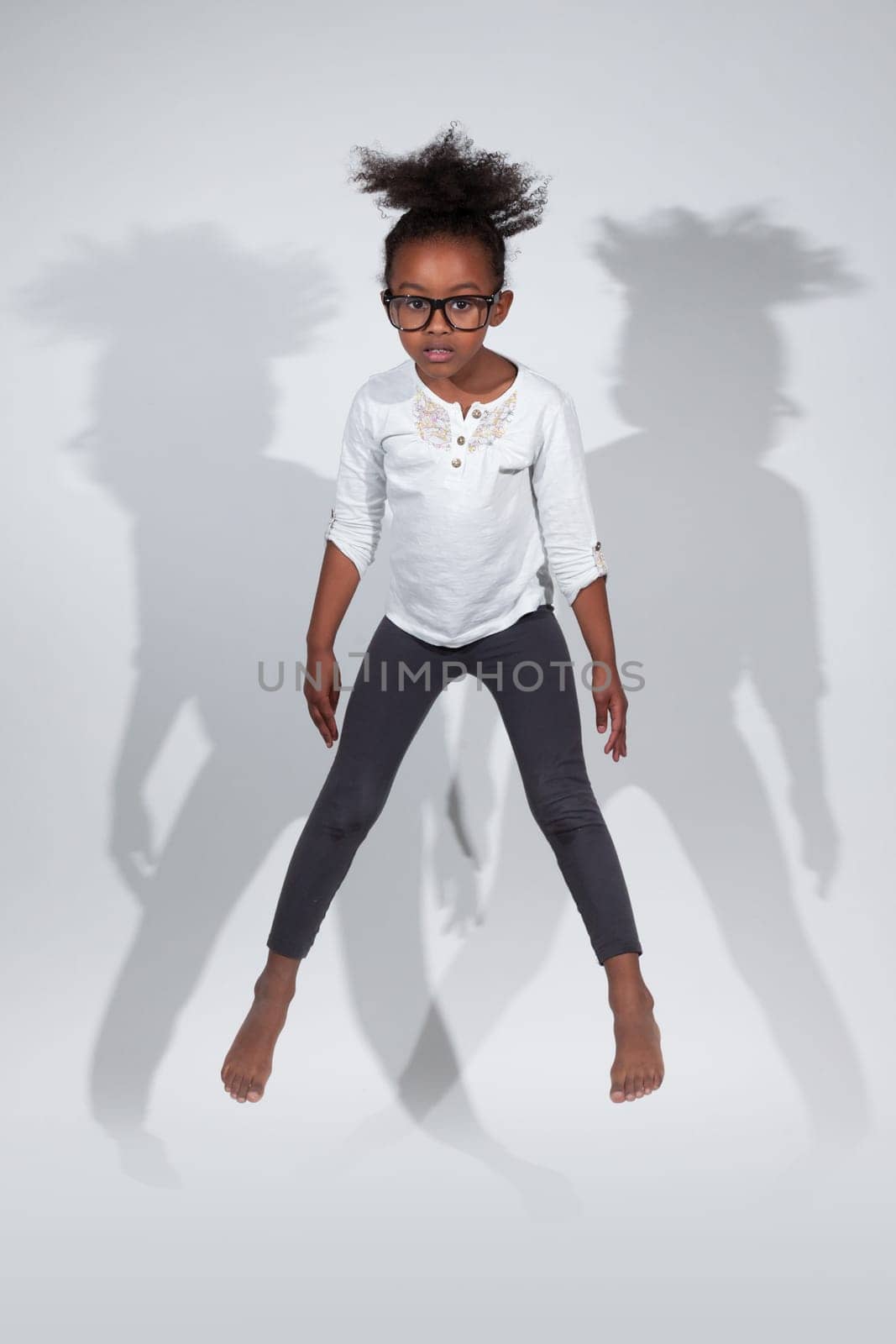 Portrait of cute Young African American girl jumping, over gray background