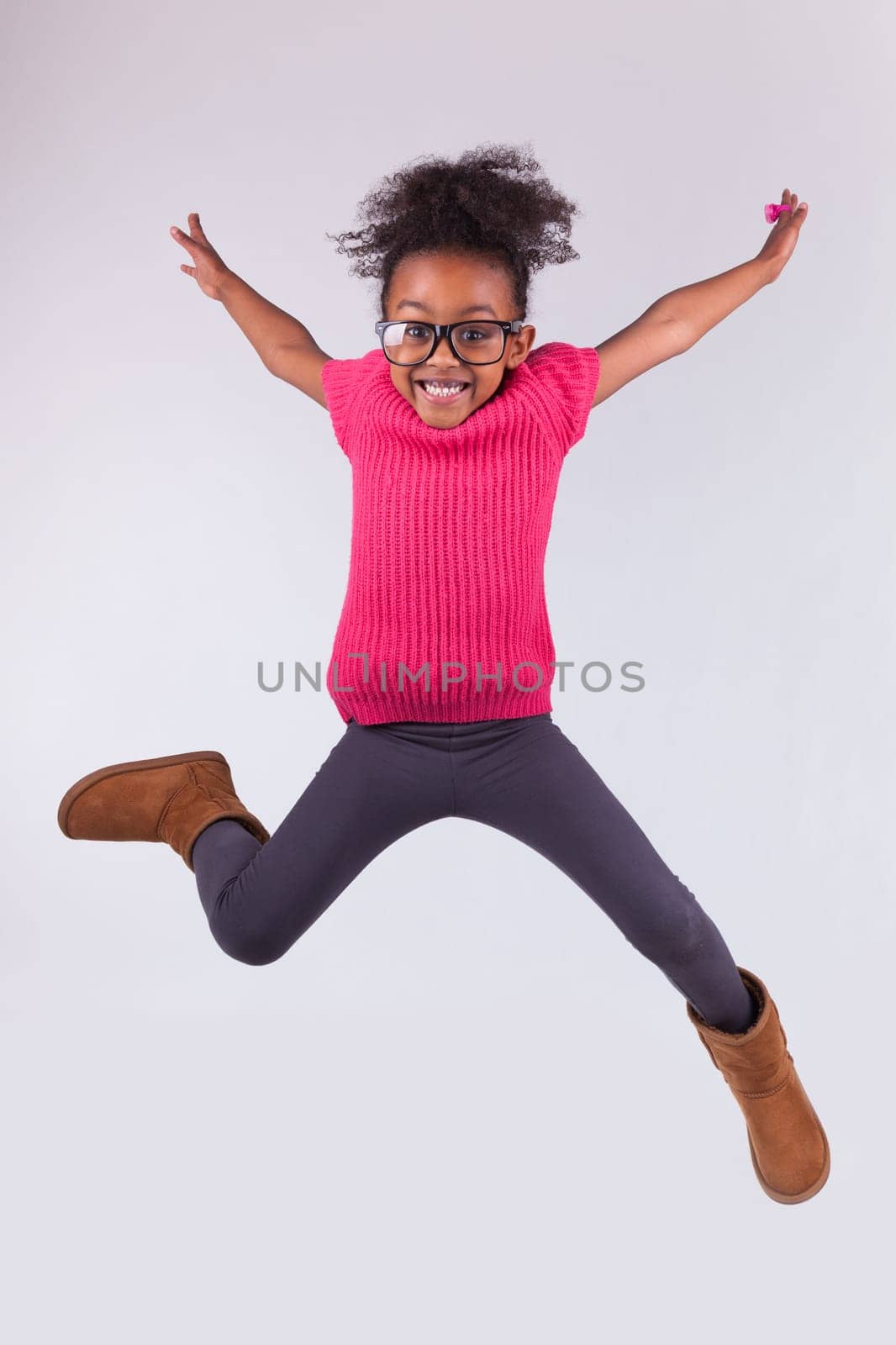 Portrait of cute Young African American girl jumping, over gray background