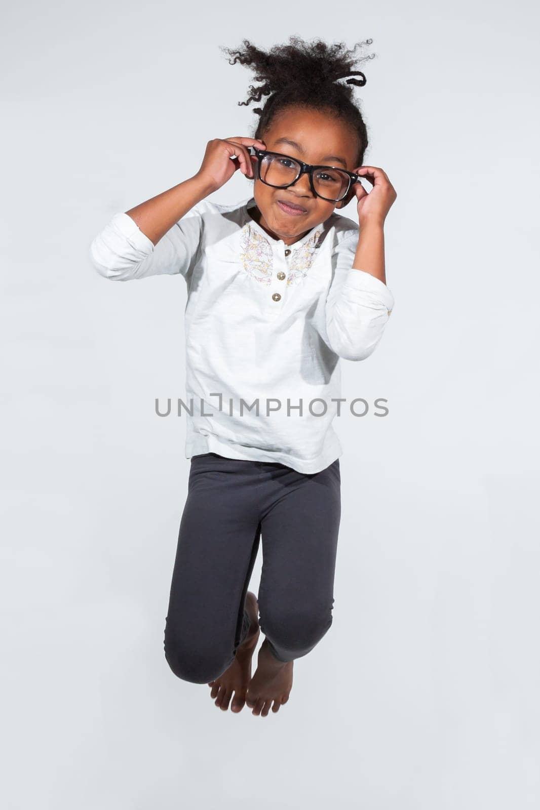 Portrait of cute Young African American girl jumping, over gray background