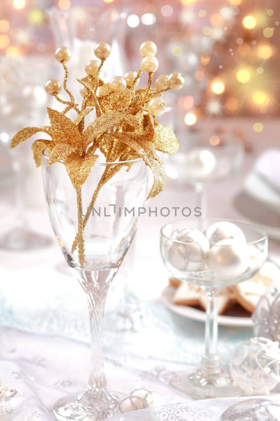 Golden branch on Christmas table. Place setting in white and golden tone.