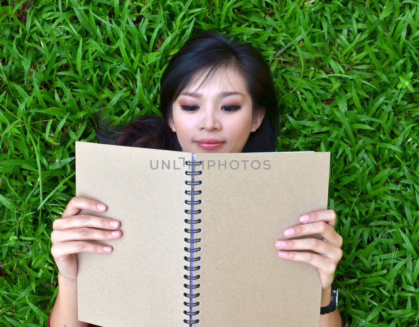 Woman lying on grass with a book