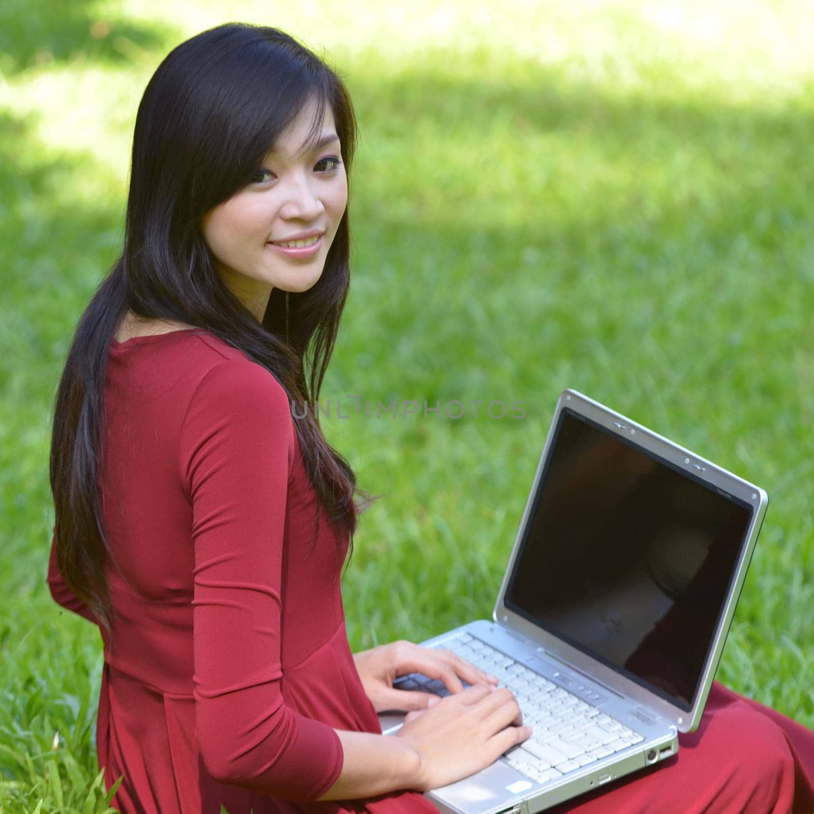 pretty  woman with laptop on green grass at the garden