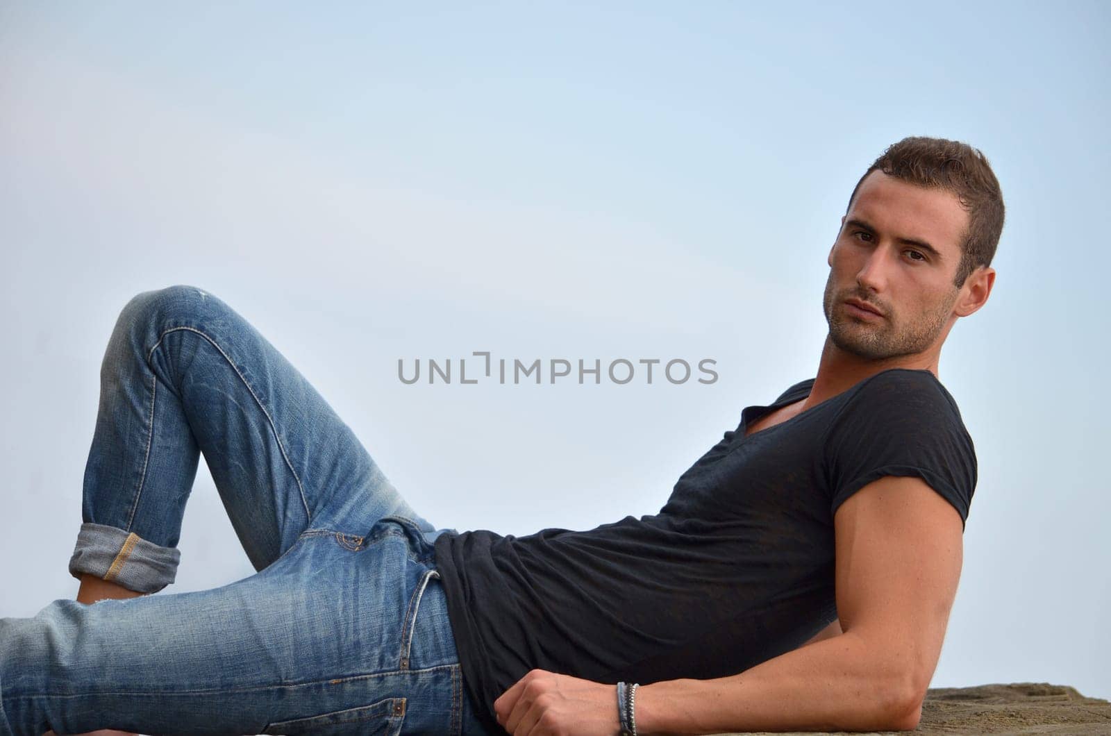 Attractive and athletic young man laying on a rock