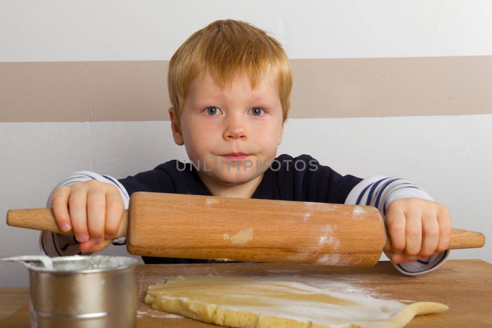 Child rolls out dough with a rolling pin
