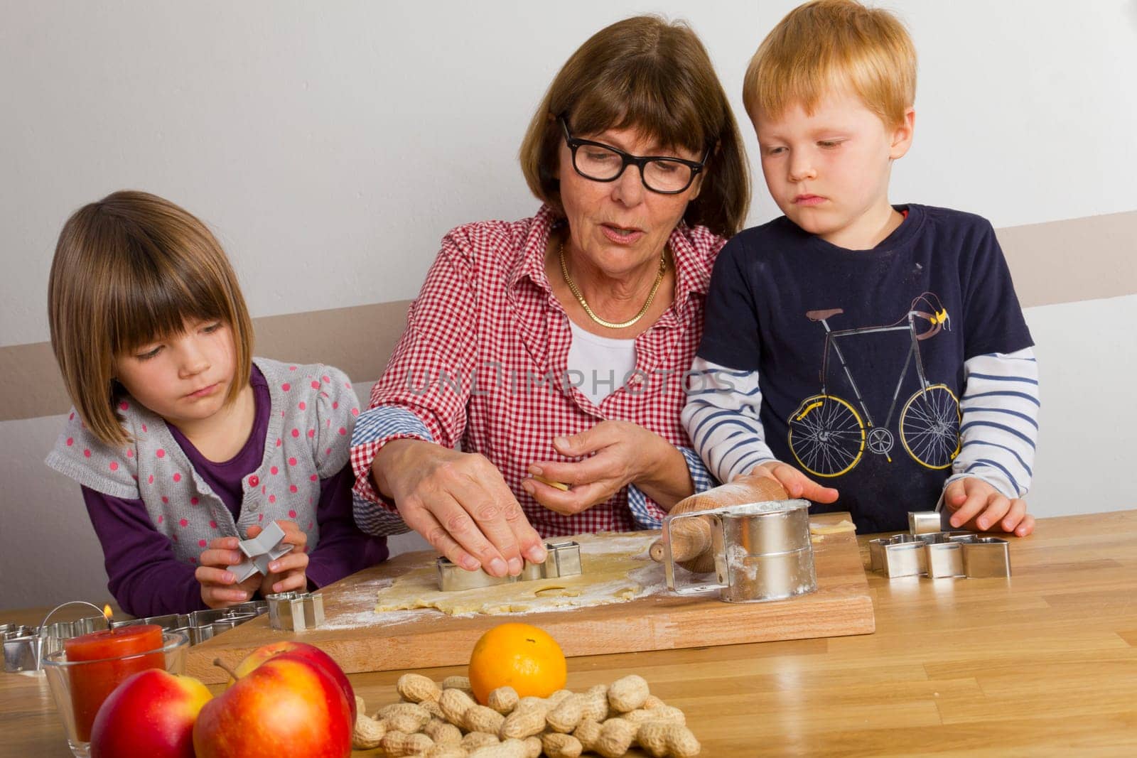 Grandma and grandchildren cut out cookies