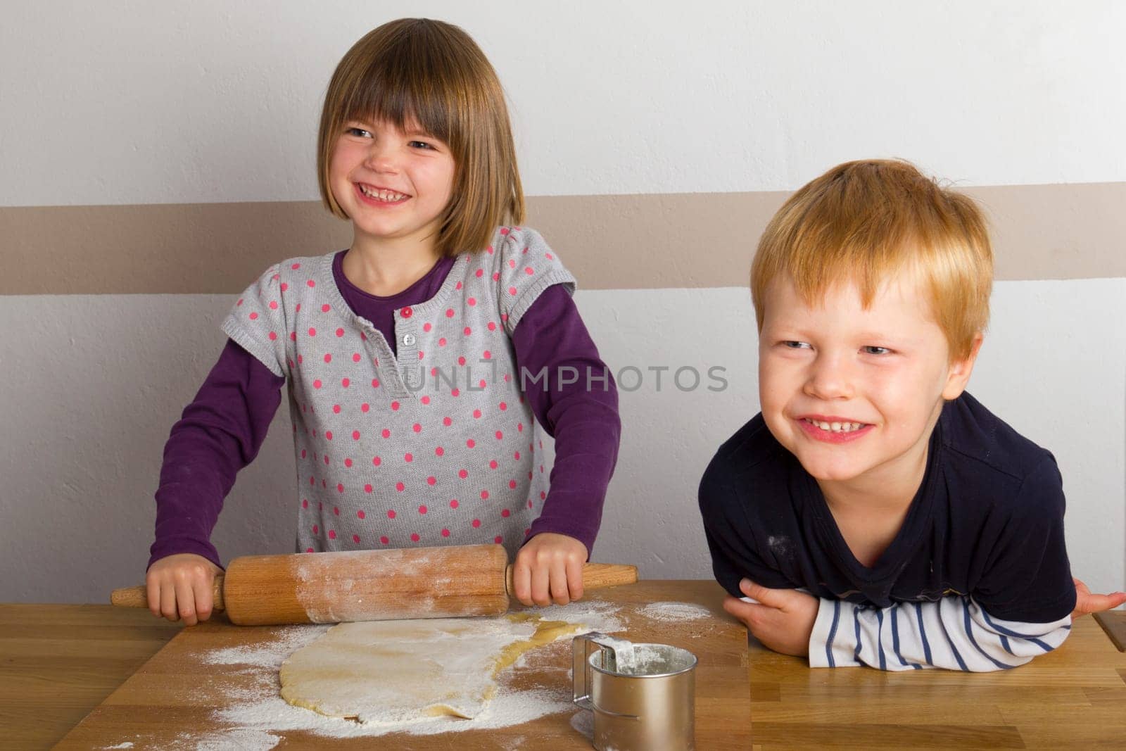 Children roll out dough with a rolling pin