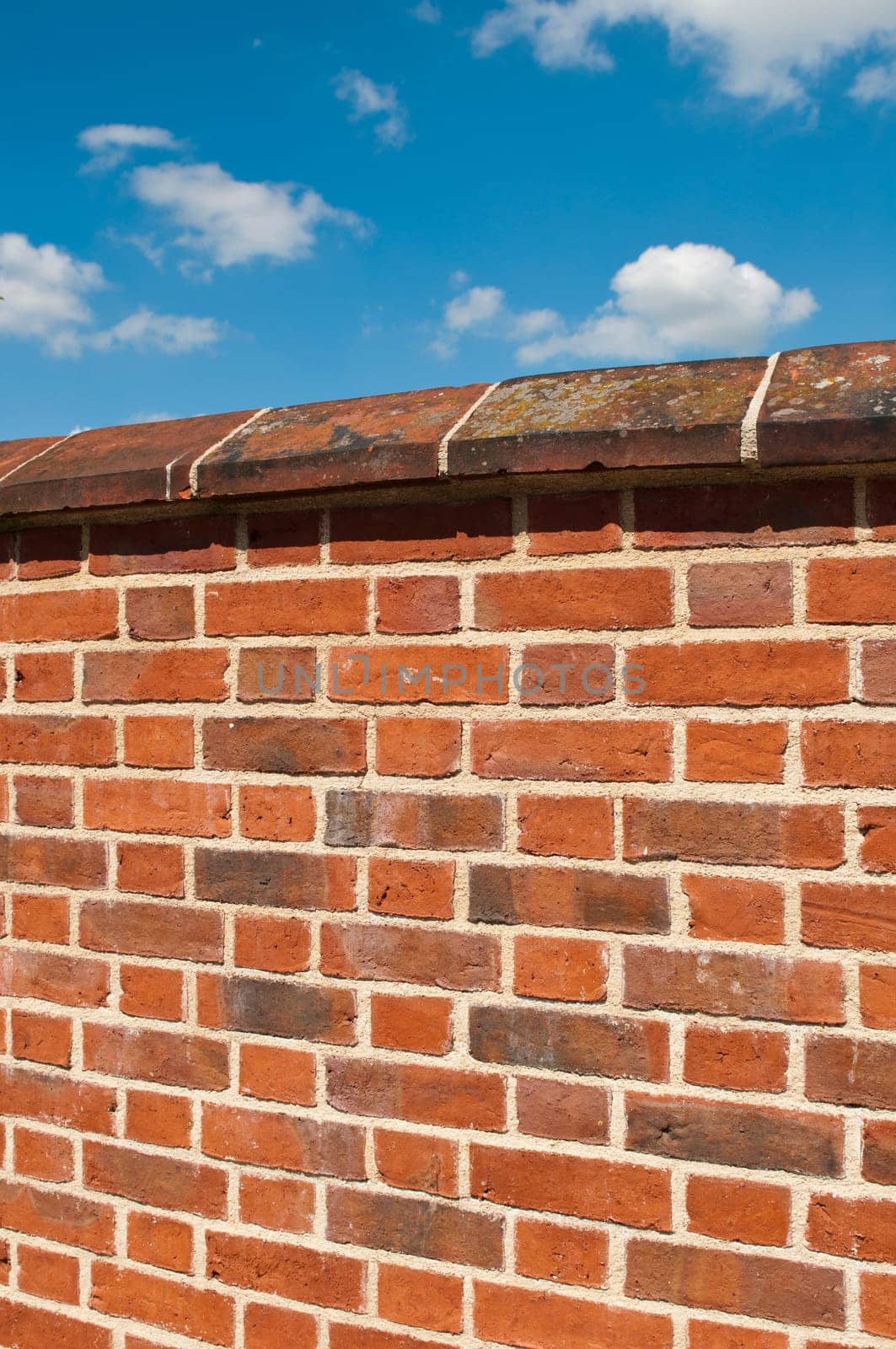 red brick wall against a gorgeous blue sky with clouds