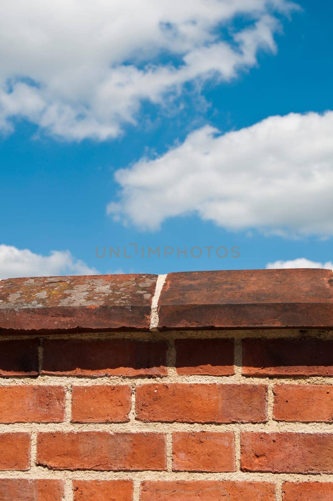 red brick wall against a gorgeous blue sky with clouds