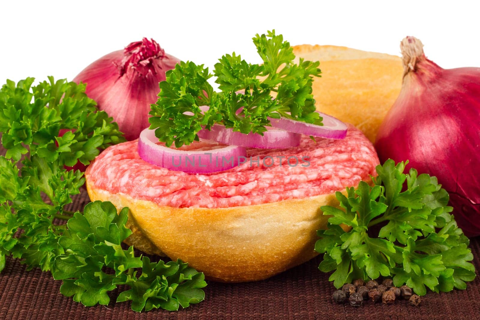 Meat rolls with parsley and onions on a bamboo mat.