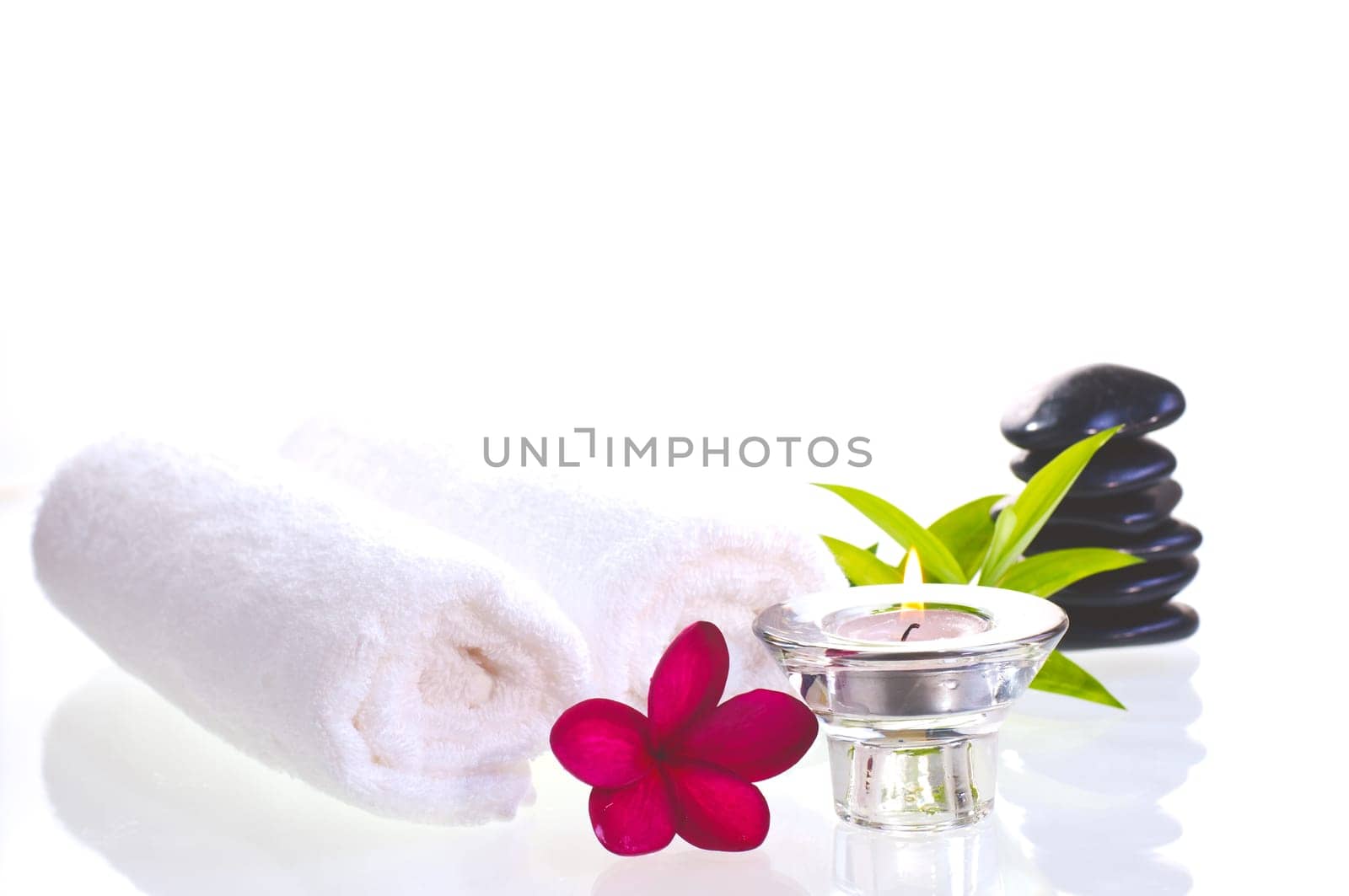 Spa concept with black zen stones and red flower over white background