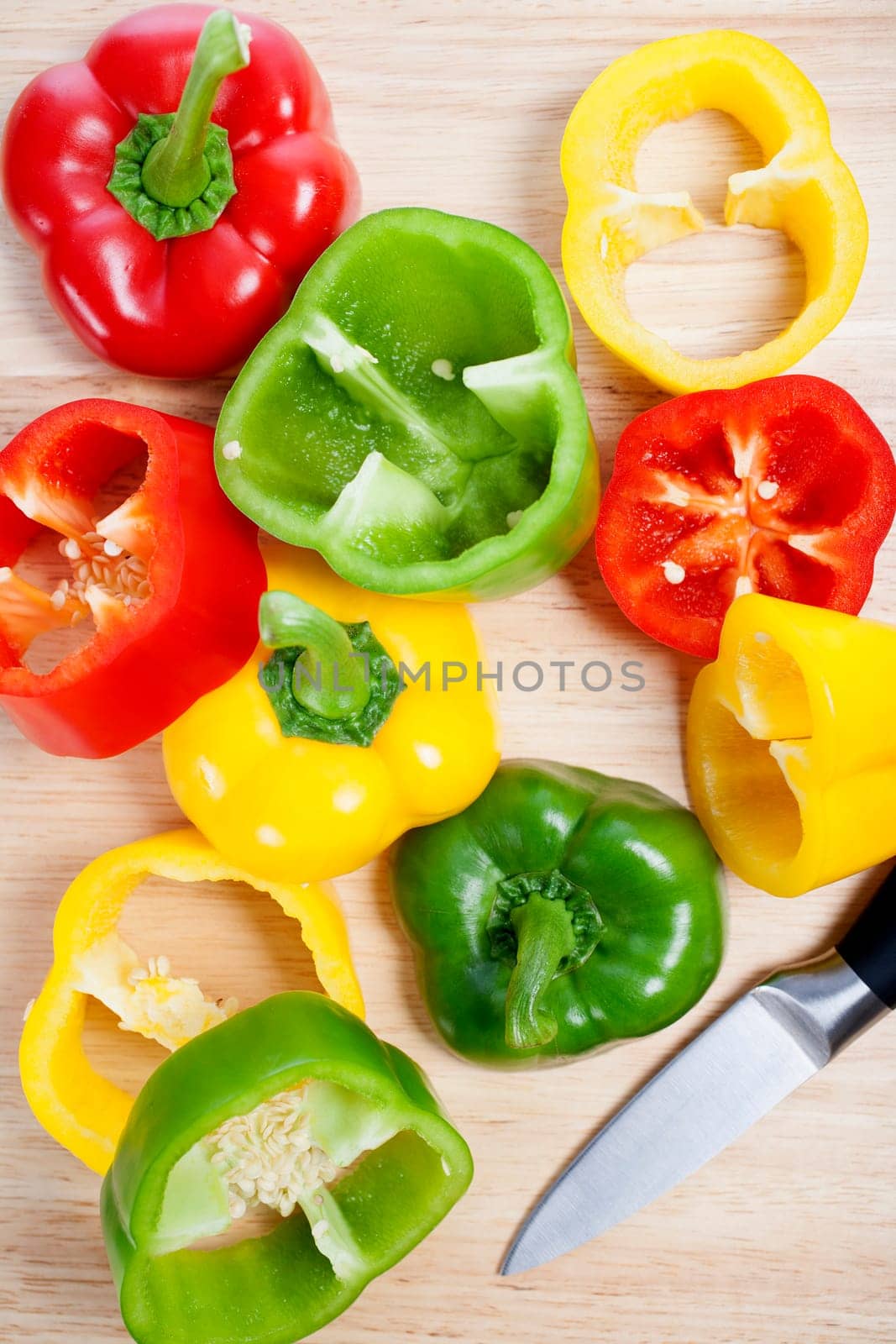 Selection of red green and yellow peppers sliced up on a chopping board