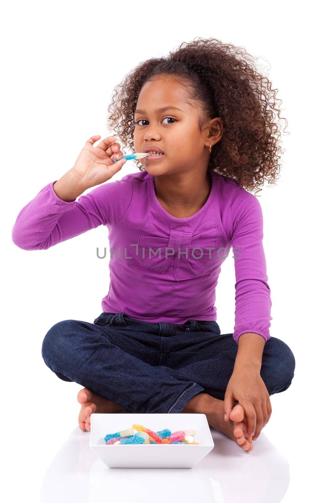 Little African Asian girl eating candy, isolated on white background