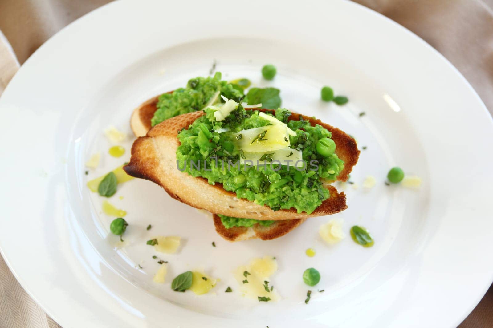 Delicious green pea baguettes with shaved cheese and mint with avocado oil.