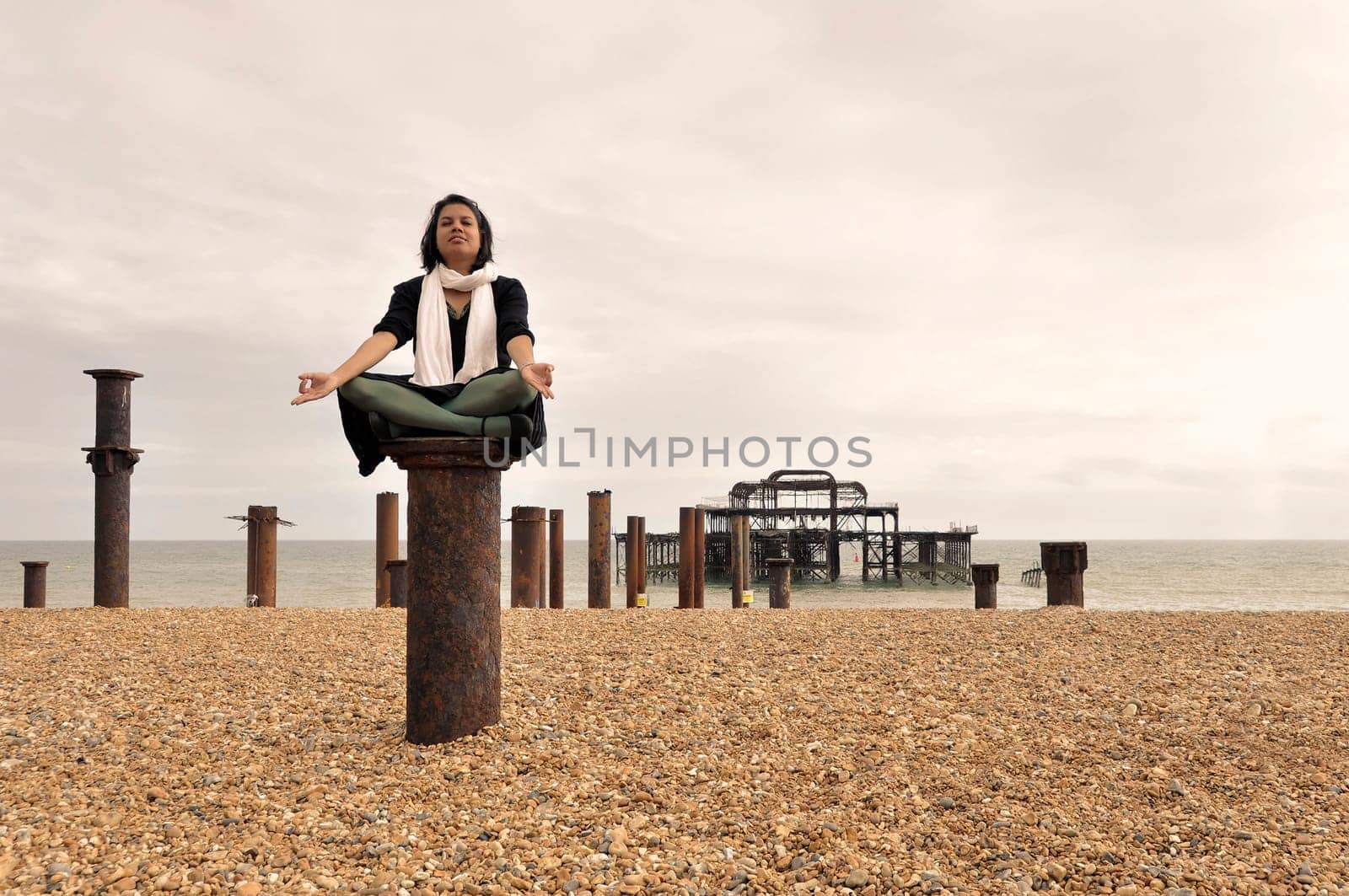Young Asian woman meditating next to the West Pier in Brighton, England, UK