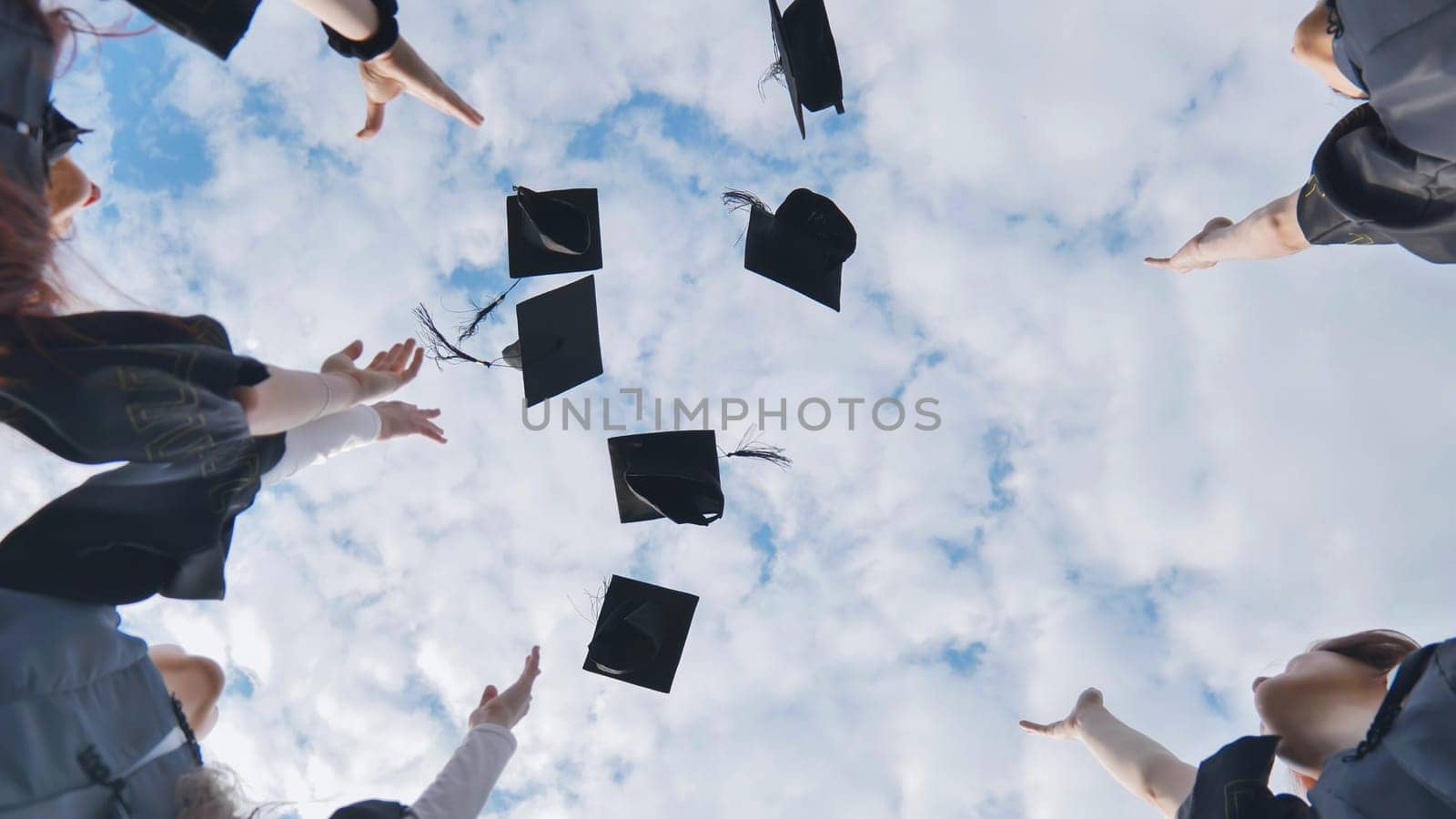 Happy group of graduated young students throwing hats