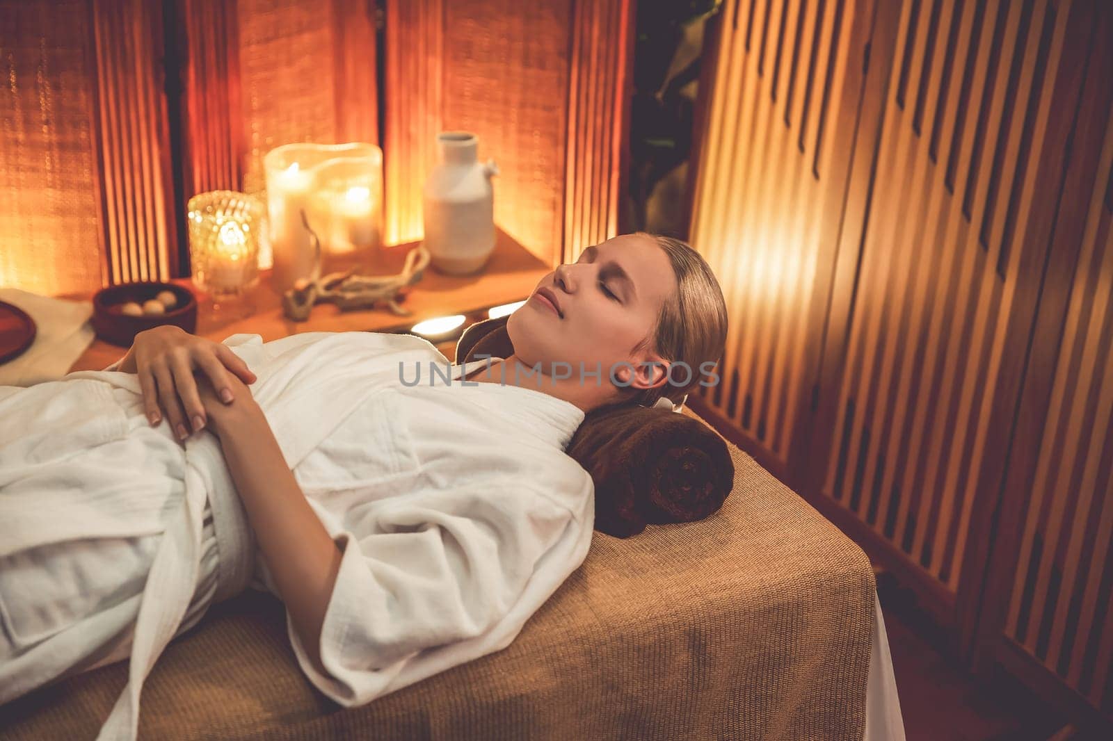 Caucasian woman customer enjoying relaxing anti-stress spa massage and pampering with beauty skin recreation leisure in warm candle lighting ambient salon spa at luxury resort or hotel. Quiescent