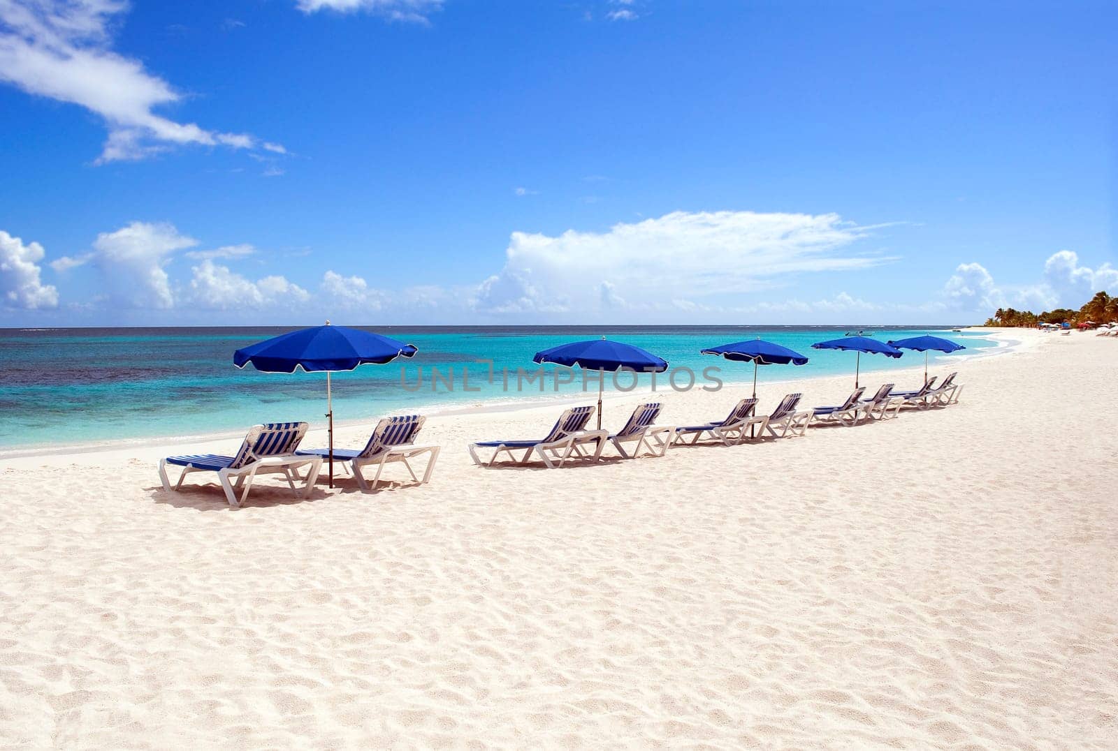 Sunbeds and beach umbrellas at beautiful caribbean beach.