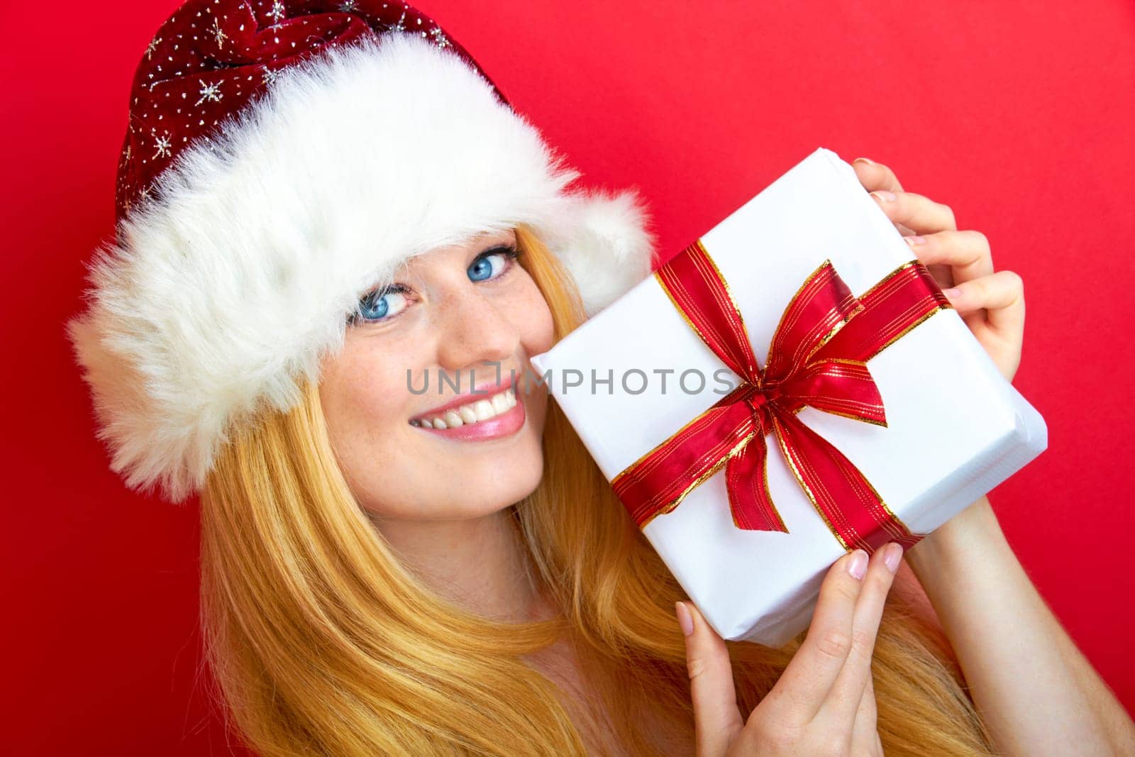beautiful blonde woman holding a christmas gift is smiling
