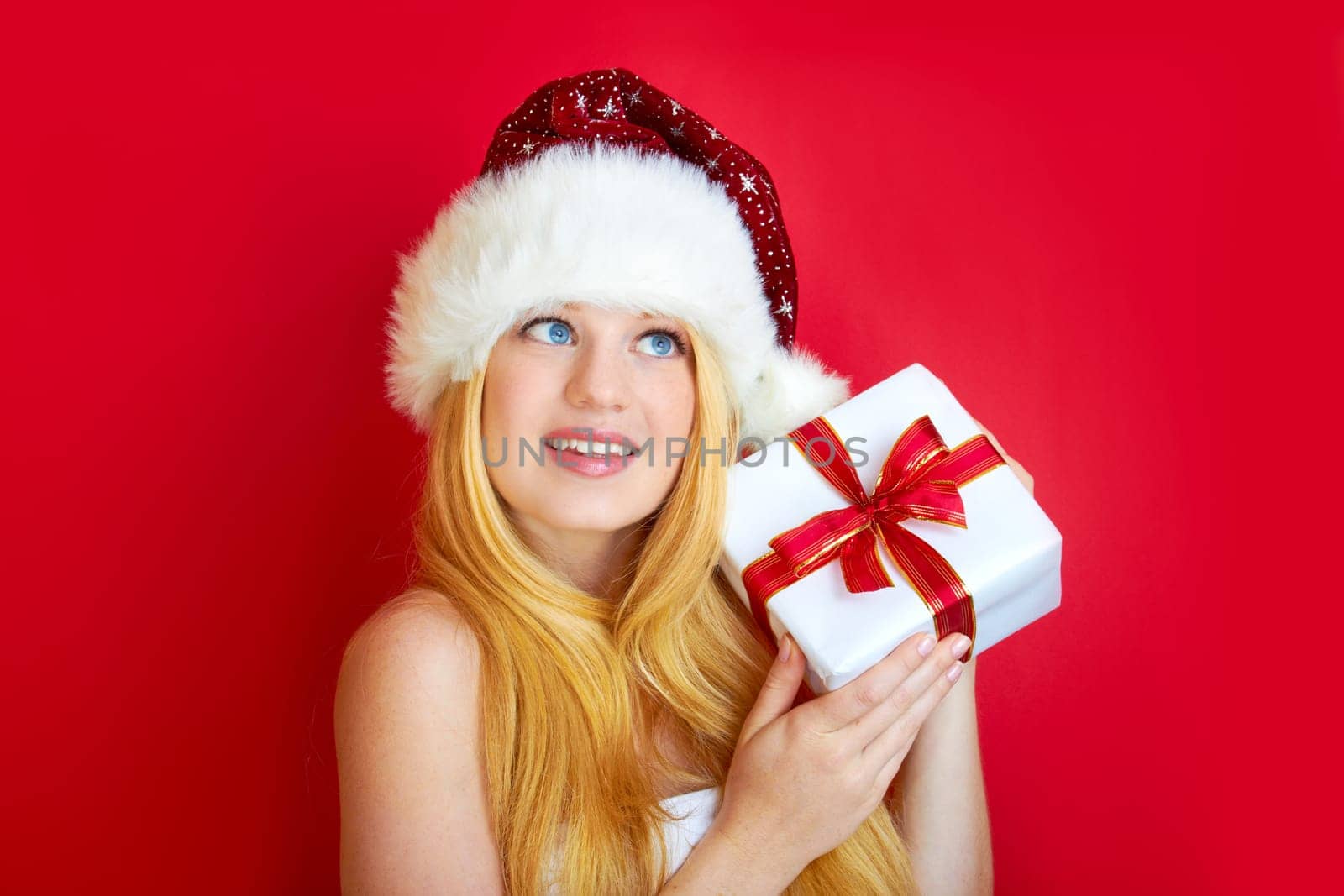 beautiful blonde woman holding a christmas gift is smiling