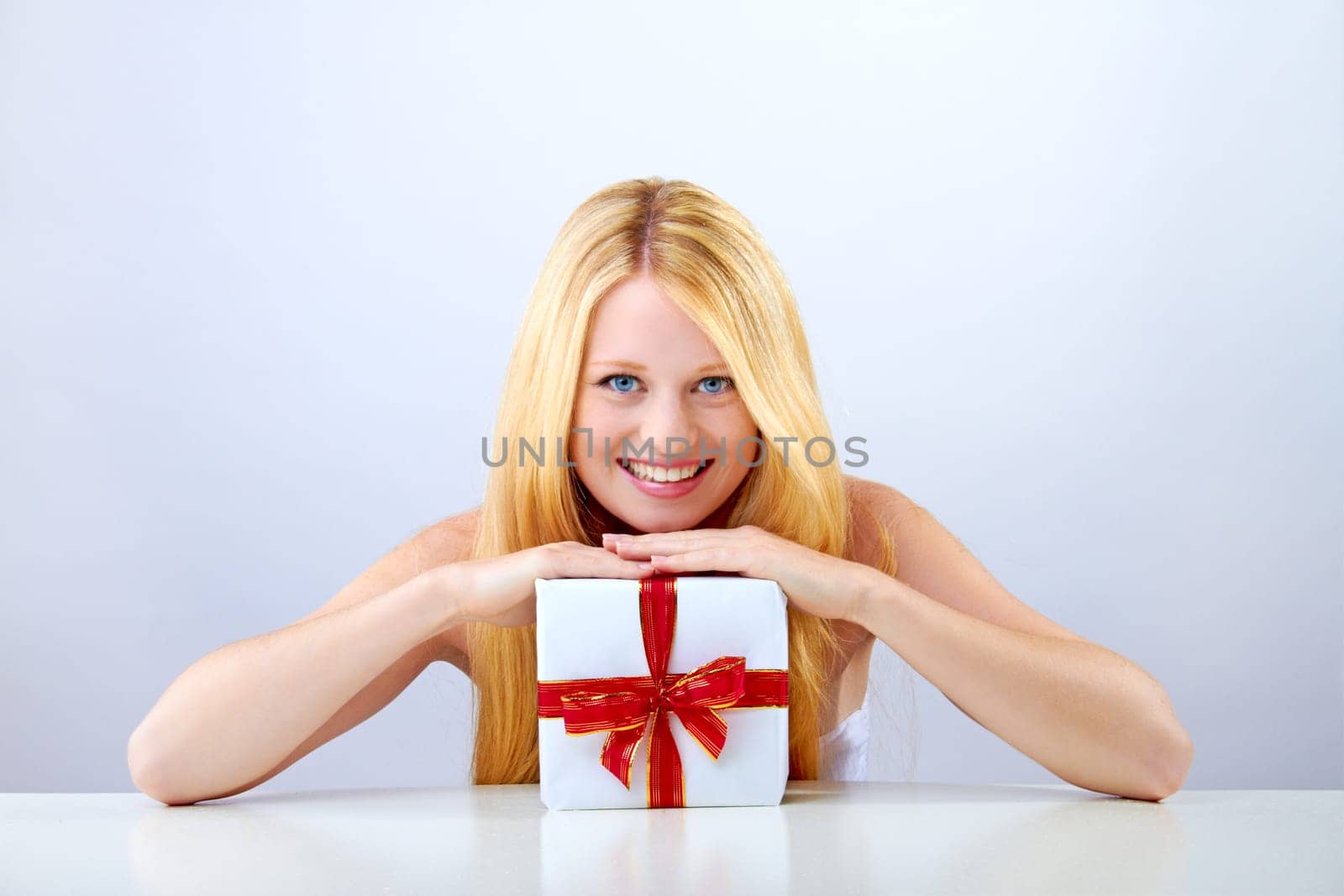 beautiful blonde woman holding a christmas gift is smiling