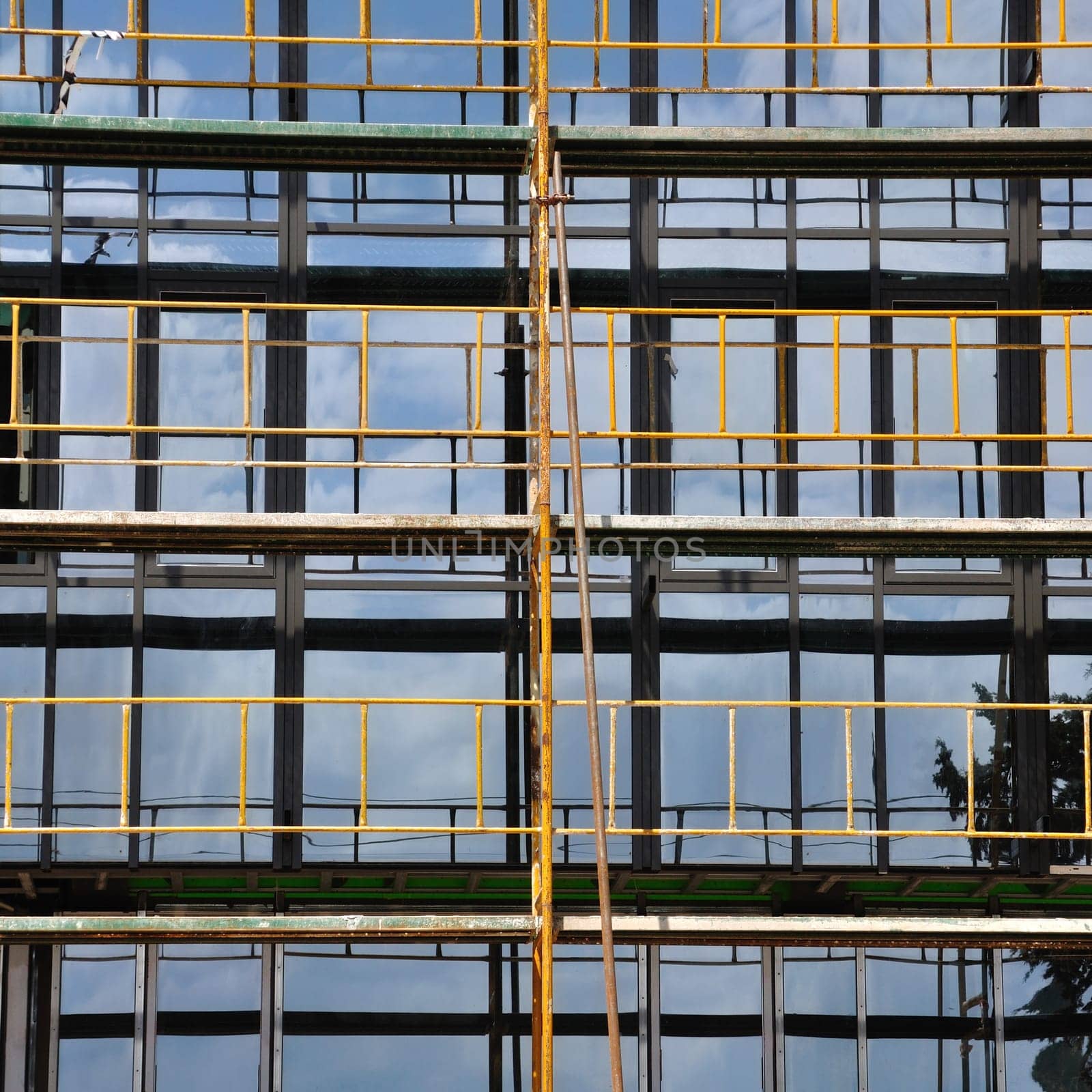 Facade windows and iron scaffold detail. Modern glass building under construction.