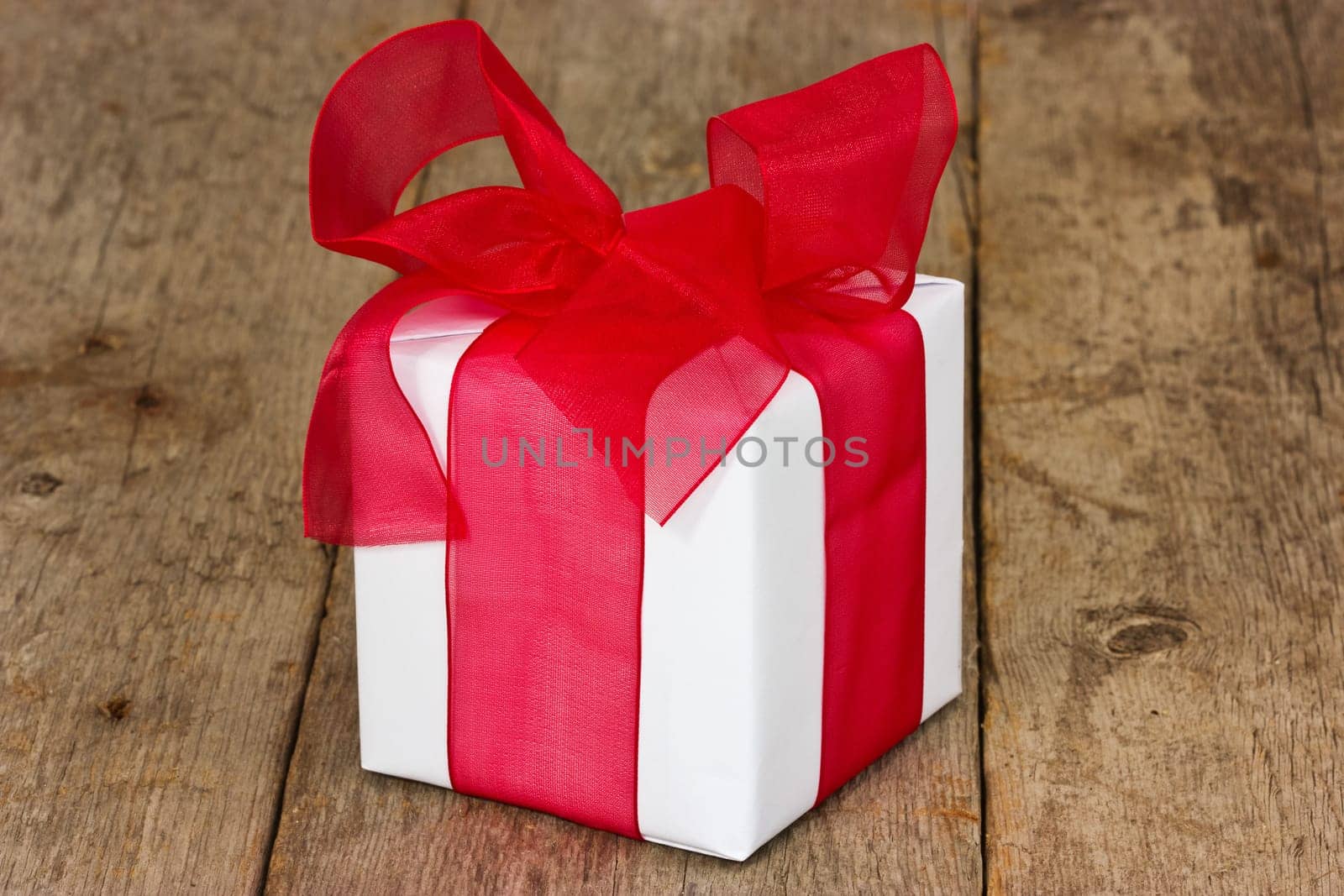 White gift box with red ribbon on the floor