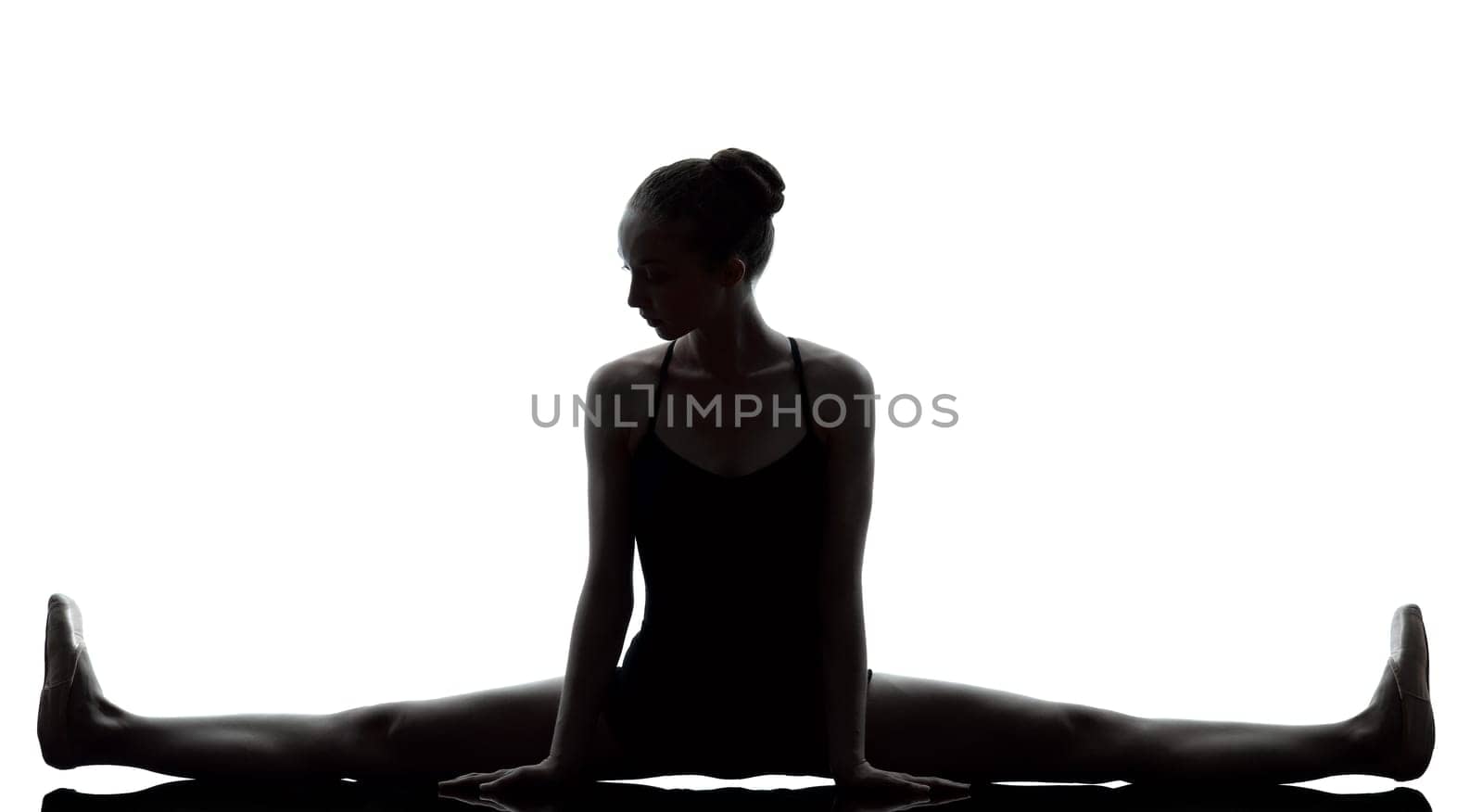 one caucasian young woman ballerina ballet dancer stretching warming up in silhouette studio on white background
