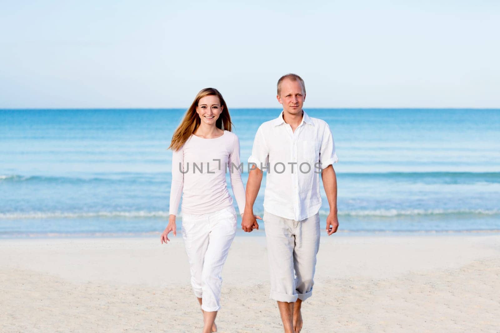 Young couple with man and woman in summer on the beach with blue sky and white clothes