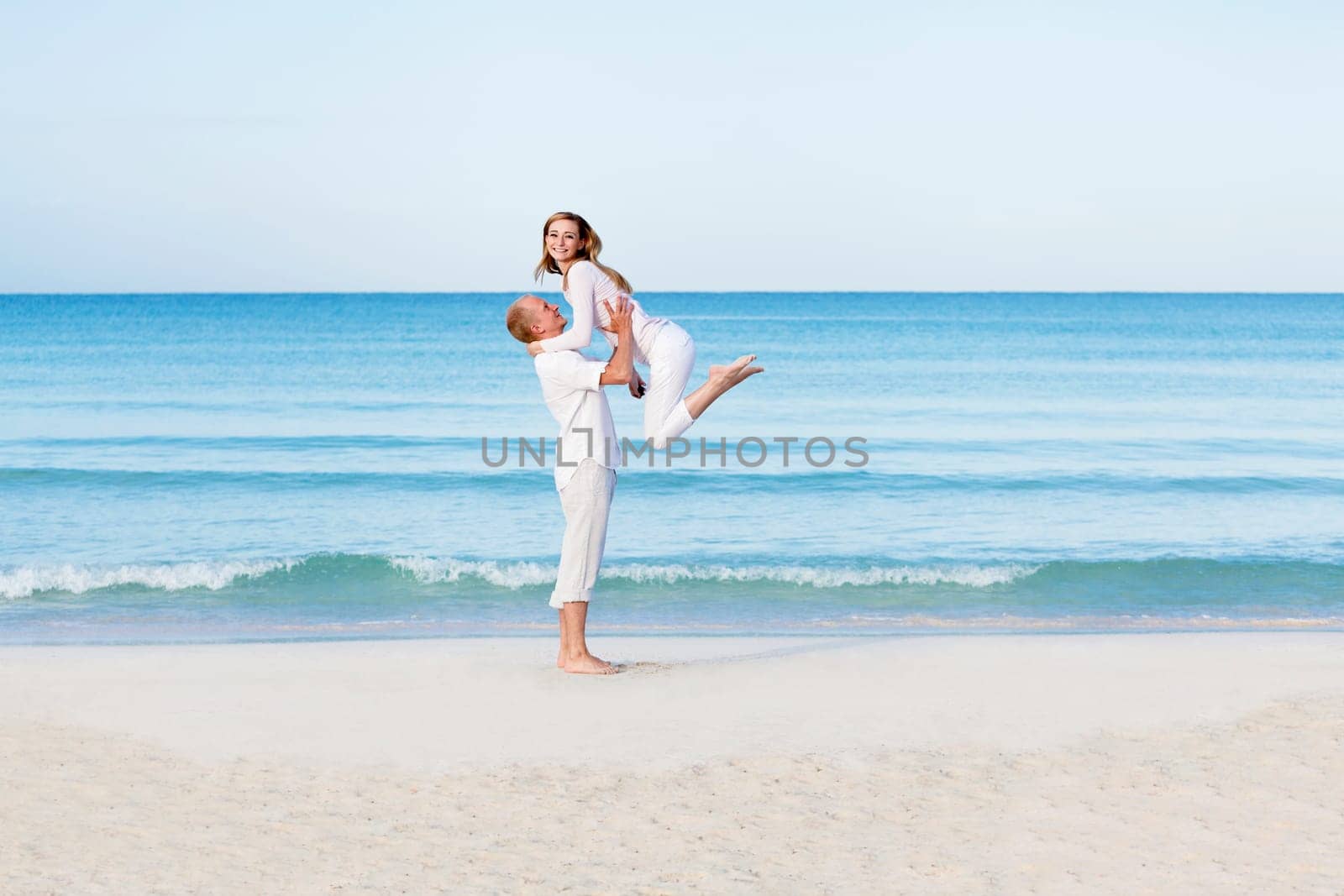 Young couple with man and woman in summer on the beach with blue sky and white clothes