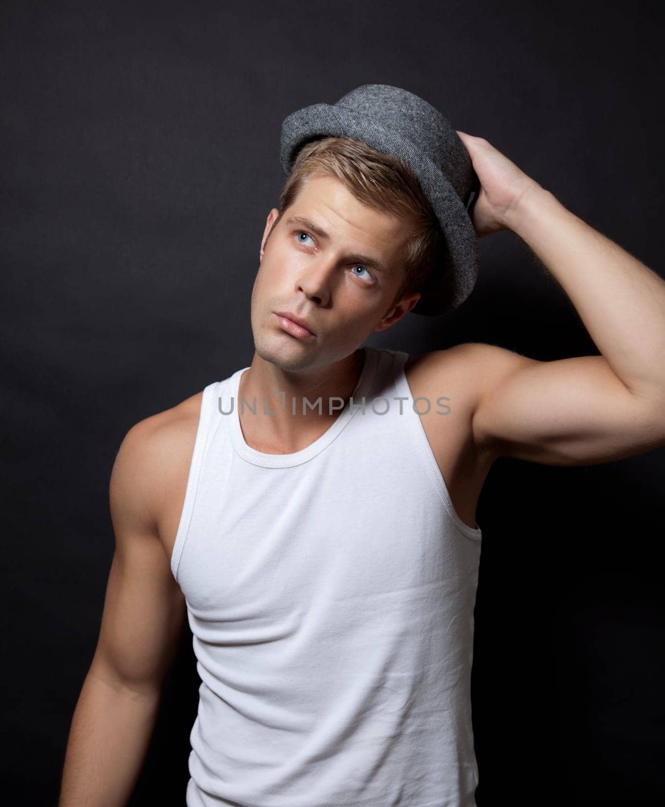 Cute muscular man wearing a hat on dark background