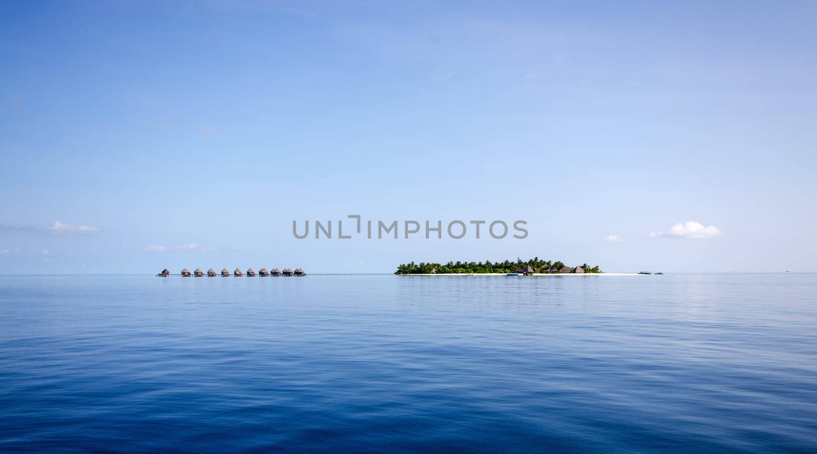 A small island in the Maldives with a number of cabins on stilts in the calm blue water