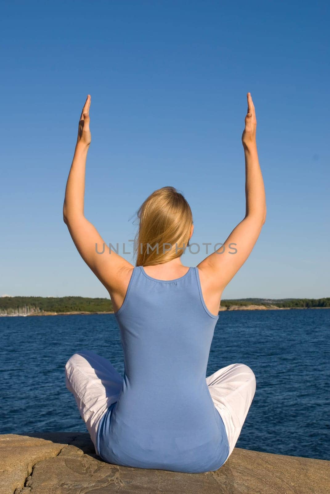 a young european woman sits by the ocean and does some yoga