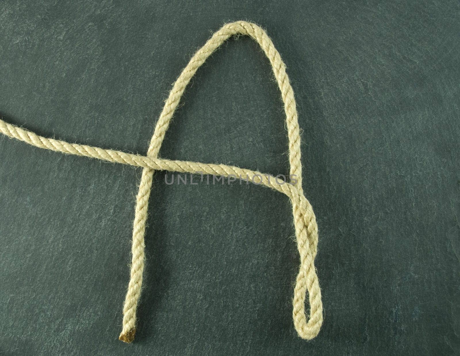 an A of rope lying on a slate table, symbolizing education