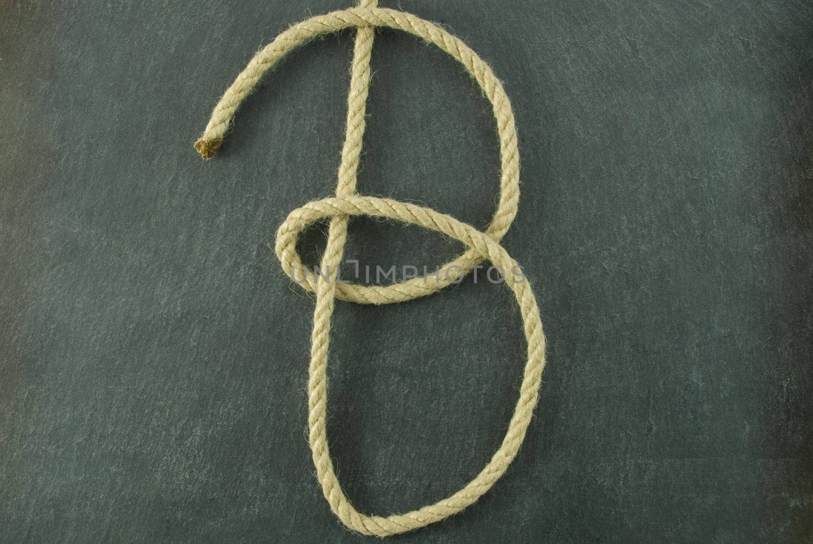 a B of rope lying on a slate table, symbolizing education and writing