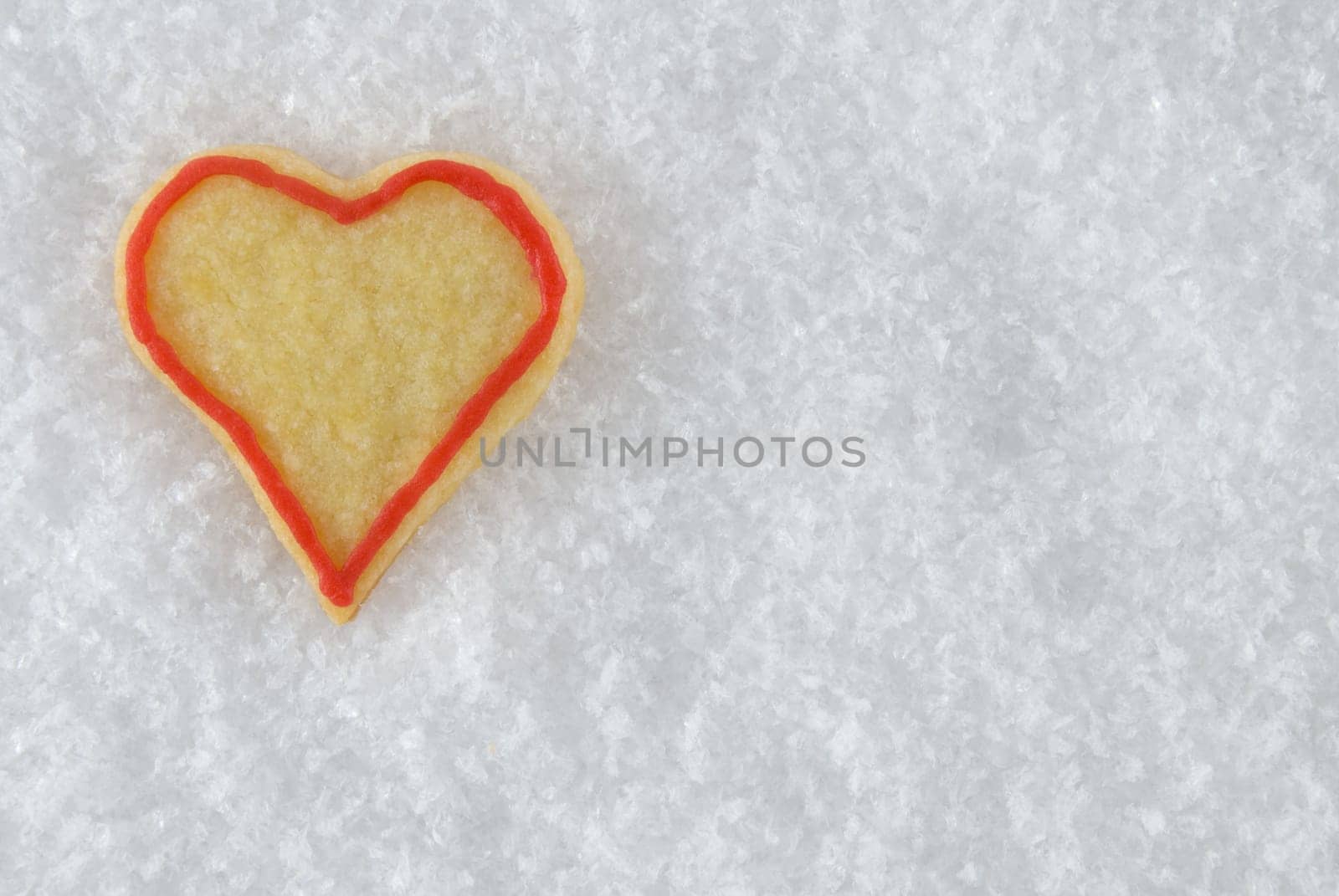 a heart christmas cookie lying in the snow