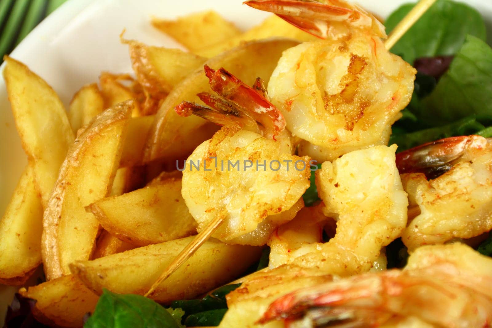 Yummy fried shrimp skewers with chunky chips ready to serve.