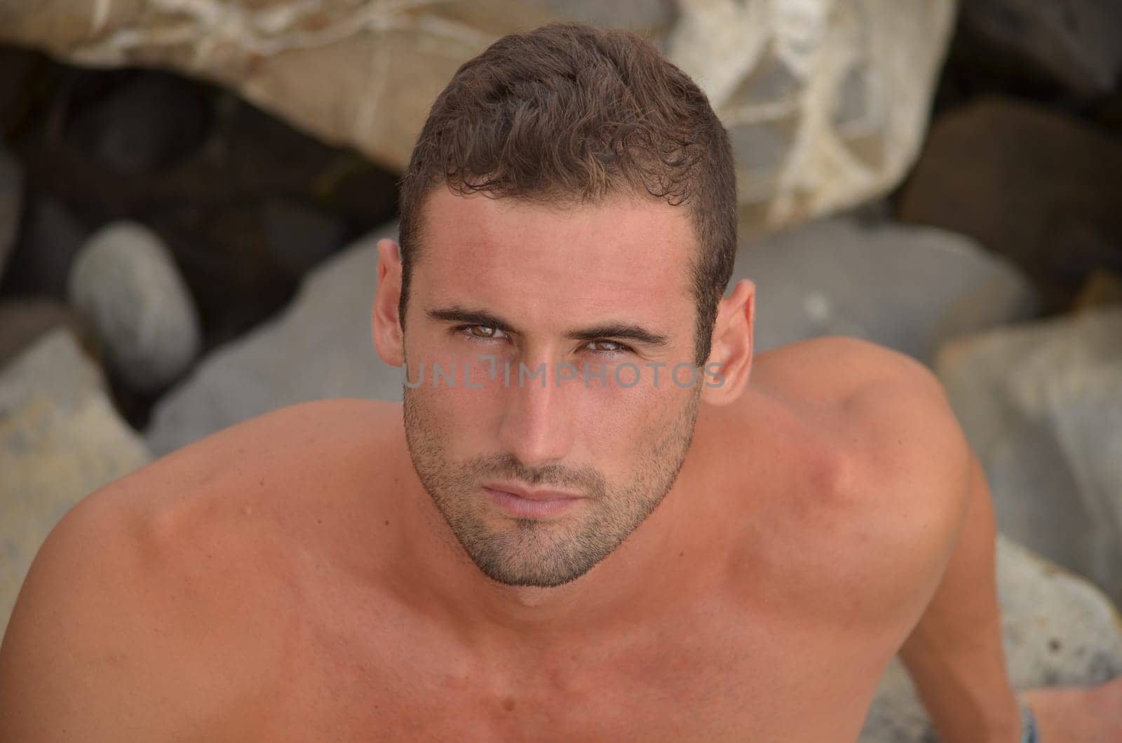 Brown eyed, shirtless young man looking up in camera