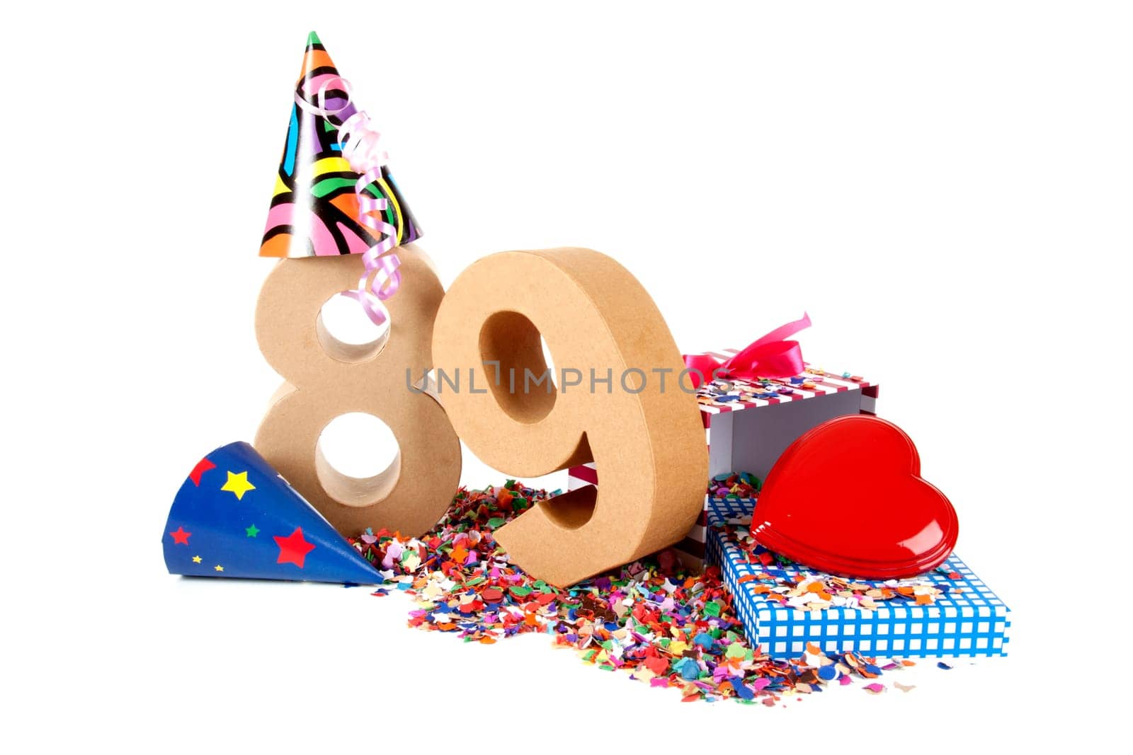 Number of age in a colorful studio setting with paper party hats, a red heart and gifts on a bottom of confettie