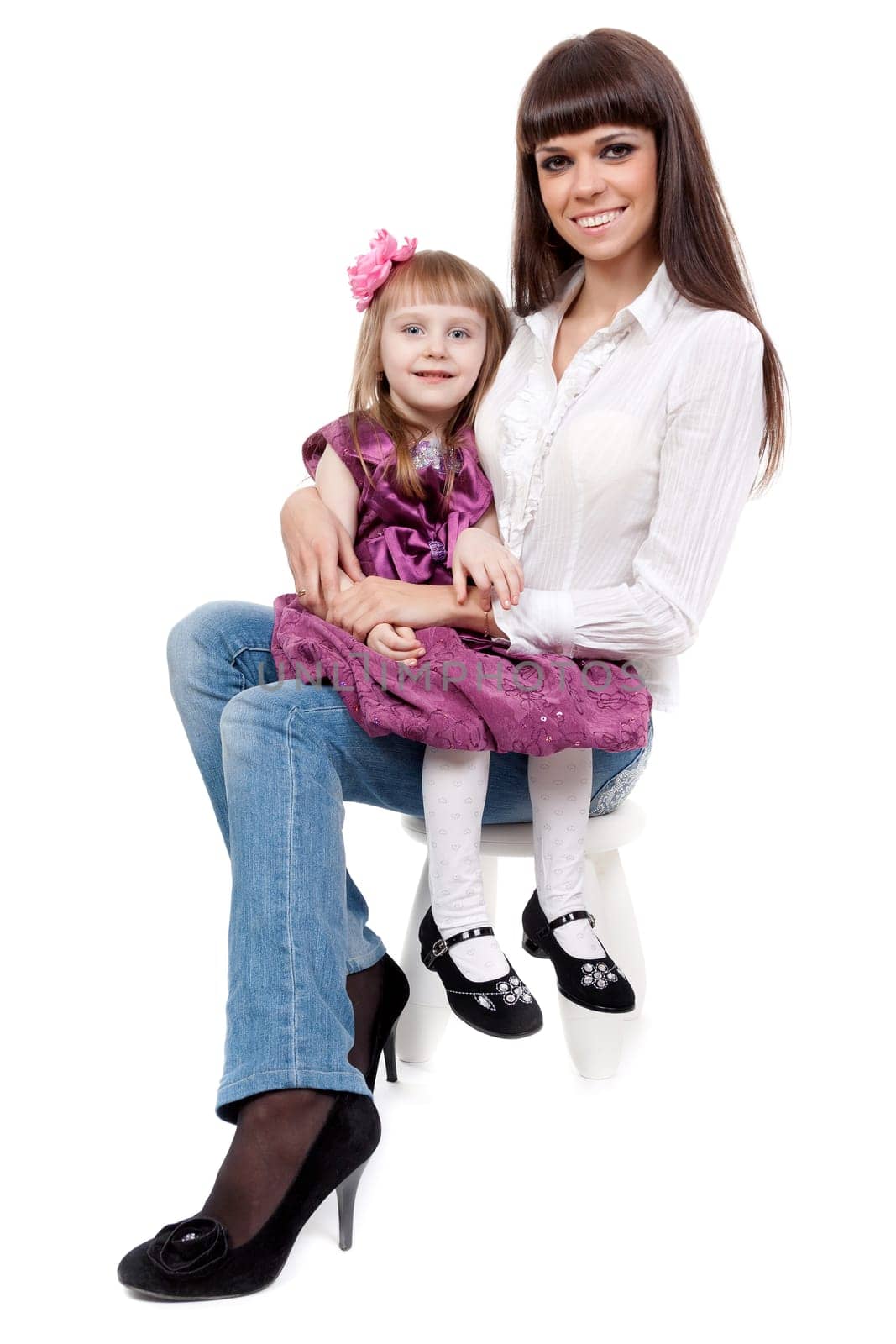 beautiful mother with a cute daughter sitting on a chair in the studio on a white background