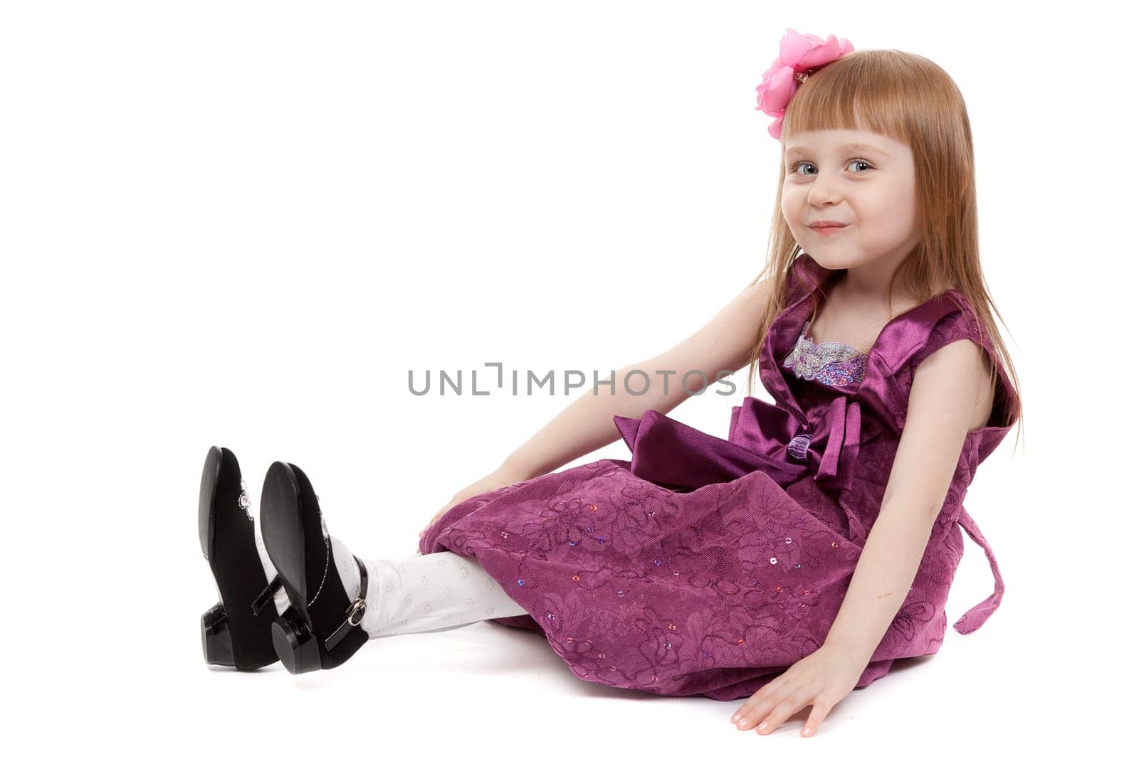 Little beautiful girl sitting on the floor in the studio. Isolate on white